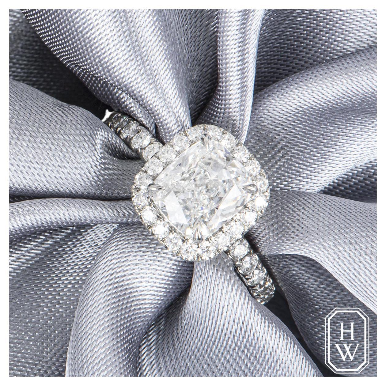 A glamorous platinum diamond engagement ring by Harry Winston from The One collection. The ring is set to the centre in a four claw mount with a cushion cut diamond weighing 1.76ct, E colour and VVS1 clarity. The full eternity engagement ring