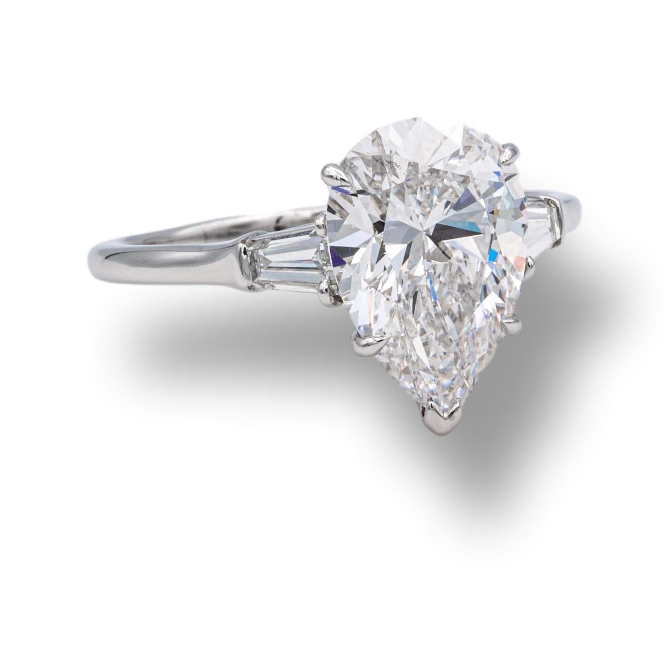 Harry Winston Platinum Pear Shape Diamond Engagement ring finely crafted in platinum with a fine GIA Certified pear shape center diamond weighing 3.27 cts. H color SI1 clarity flanked by two tapered baguette diamonds weighing .43 carats total