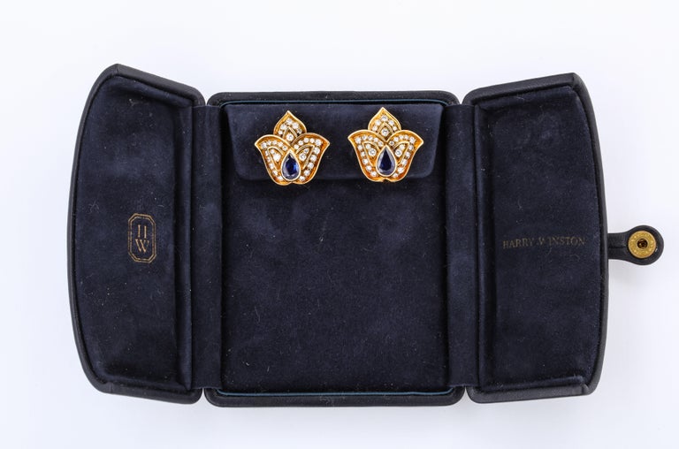 This lovely pair of Harry Winston Sapphire Diamond Yellow Gold Tulip Clip Earrings is offered here in their original case. They are composed of 2 pear shaped sapphires and Fine White Full Cut Diamonds, and are set in 18k Yellow Gold.

Materials:
18k