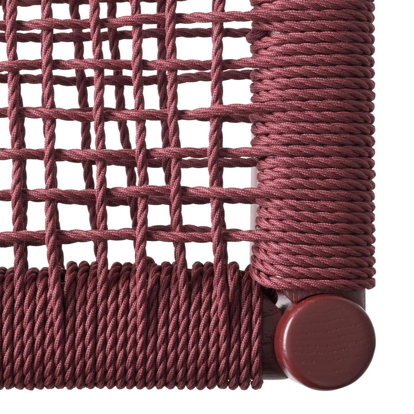Harry's 815 by Luigi Billiani is designed for outdoor spaces, merging traditional chair frames with Mediterranean-inspired braided marine rope in tibetan red. The ash wood frame is lacquered in RAL 3004, complementing the woven seat and backrest.