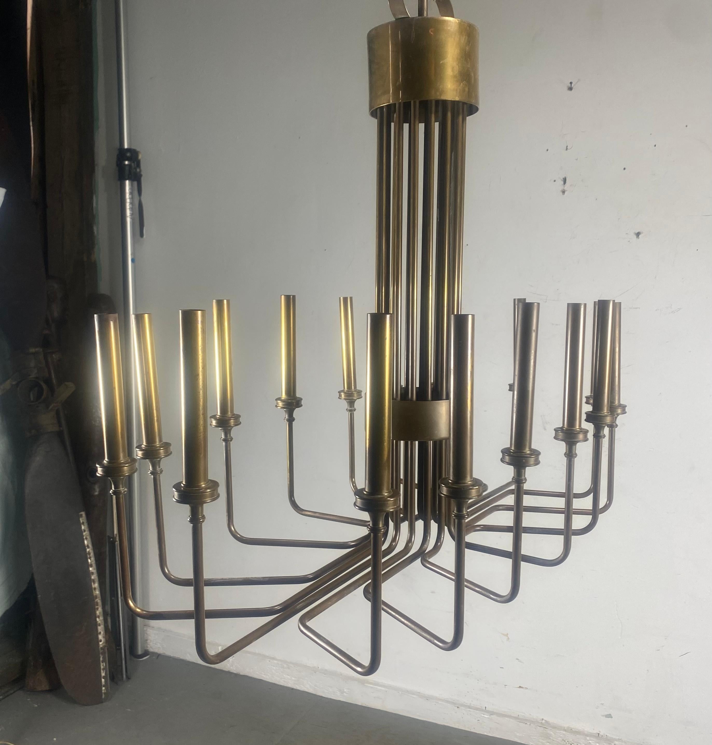 A vintage modernistic chandelier by Hart Associates, attributed to Tommi Parzinger, produced circa 1960s, entirely in brass, each of the sixteen lights supported by a curved beam, grouped in the center. This light fixture is in overall very good
