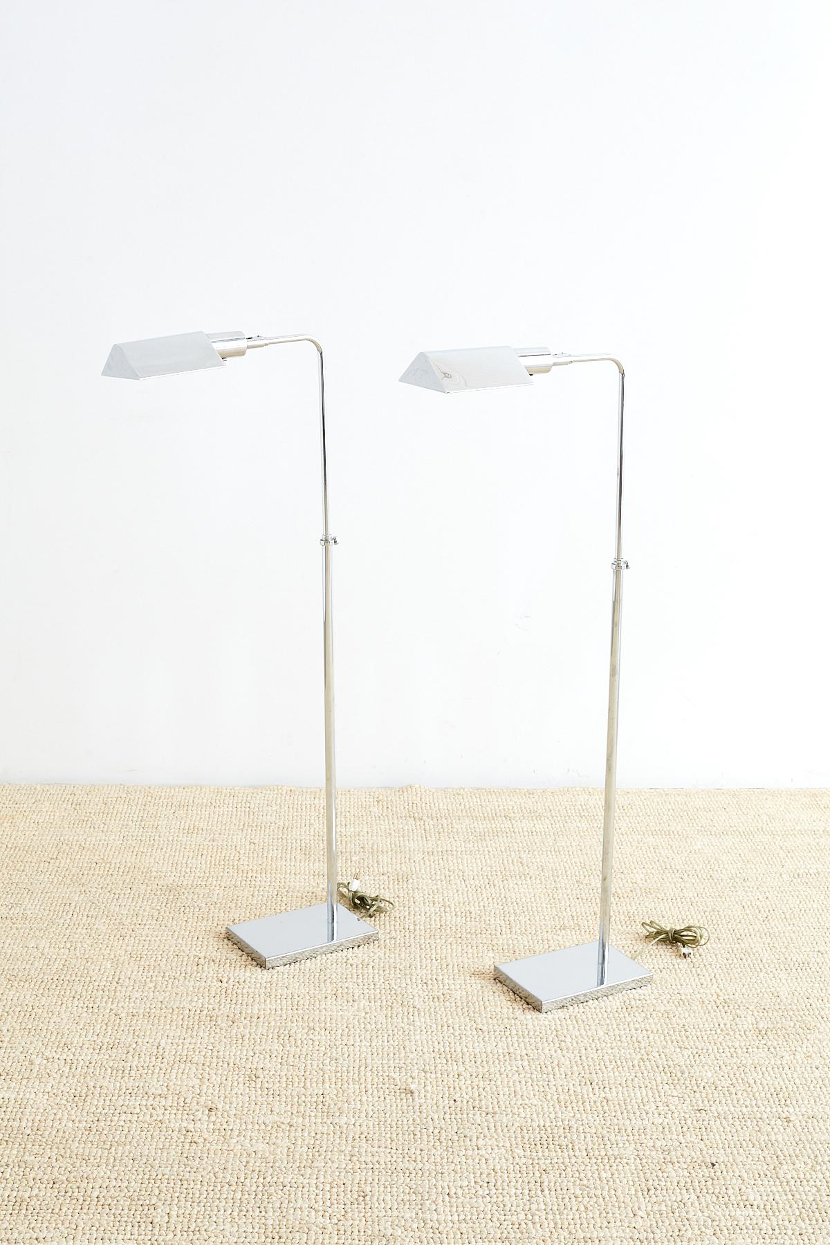 Mid-Century Modern pair of pharmacy floor lamps made in the manner and style of Cedric Hartman by Koch and Lowy's OMI lighting company. Featuring a brass metal construction with a chrome finish. Each lamp adjusts from 32 inches high to 45 inches