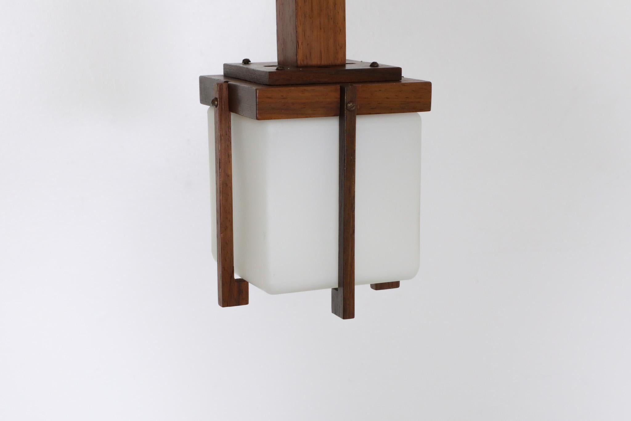 Harvey Guzzini style, Mid-Century, small Scandinavian hanging lamp in a minimalist style. Teak lantern pendant with complementing milk glass shade. In original condition with wear and some scratching consistent with age and use.