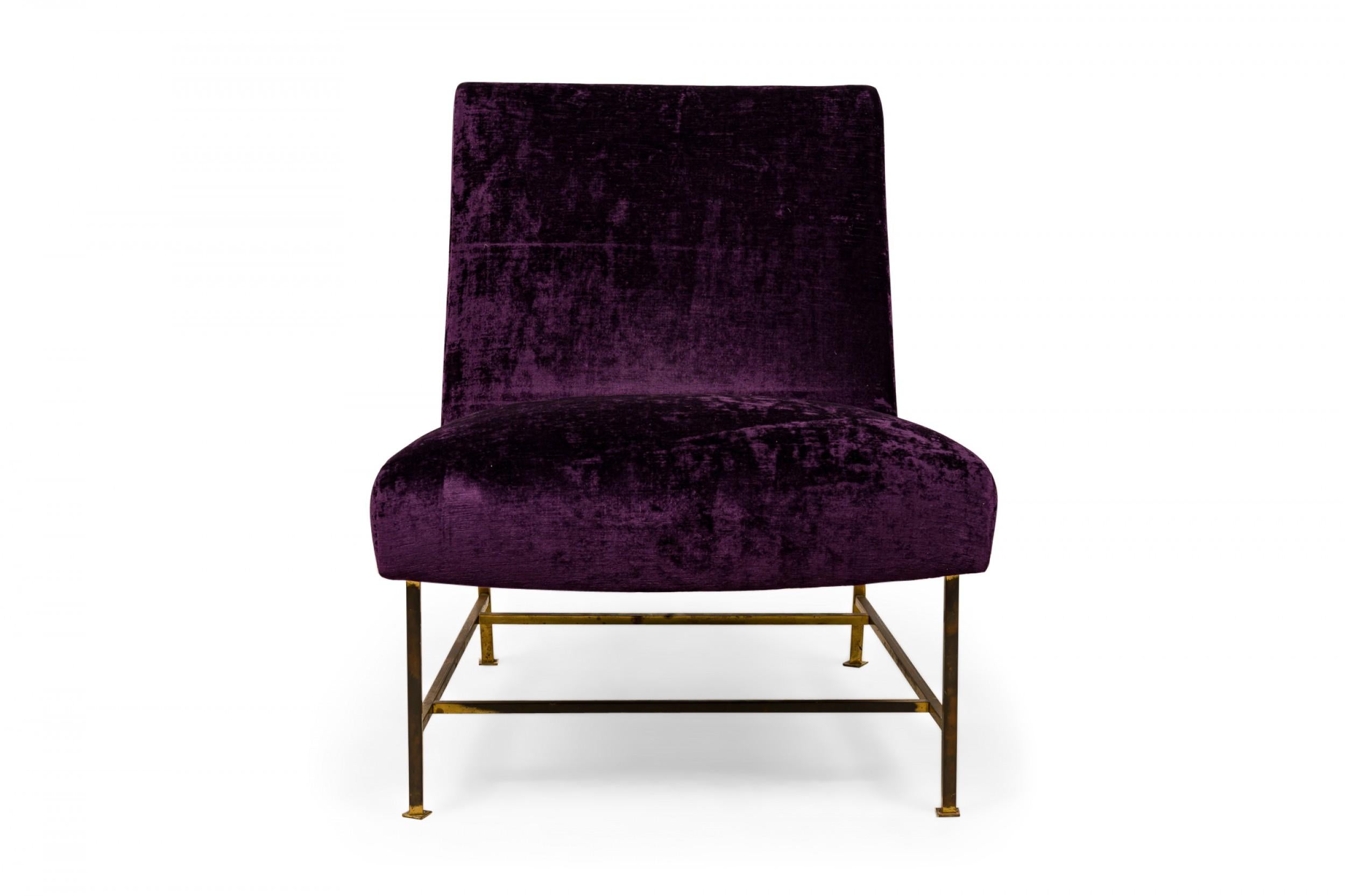American Mid-Century slipper chair with crushed purple velour upholstery resting on four brass legs with stretchers connecting the front and back legs, ending in circular feet. (HARVEY PROBBER)
