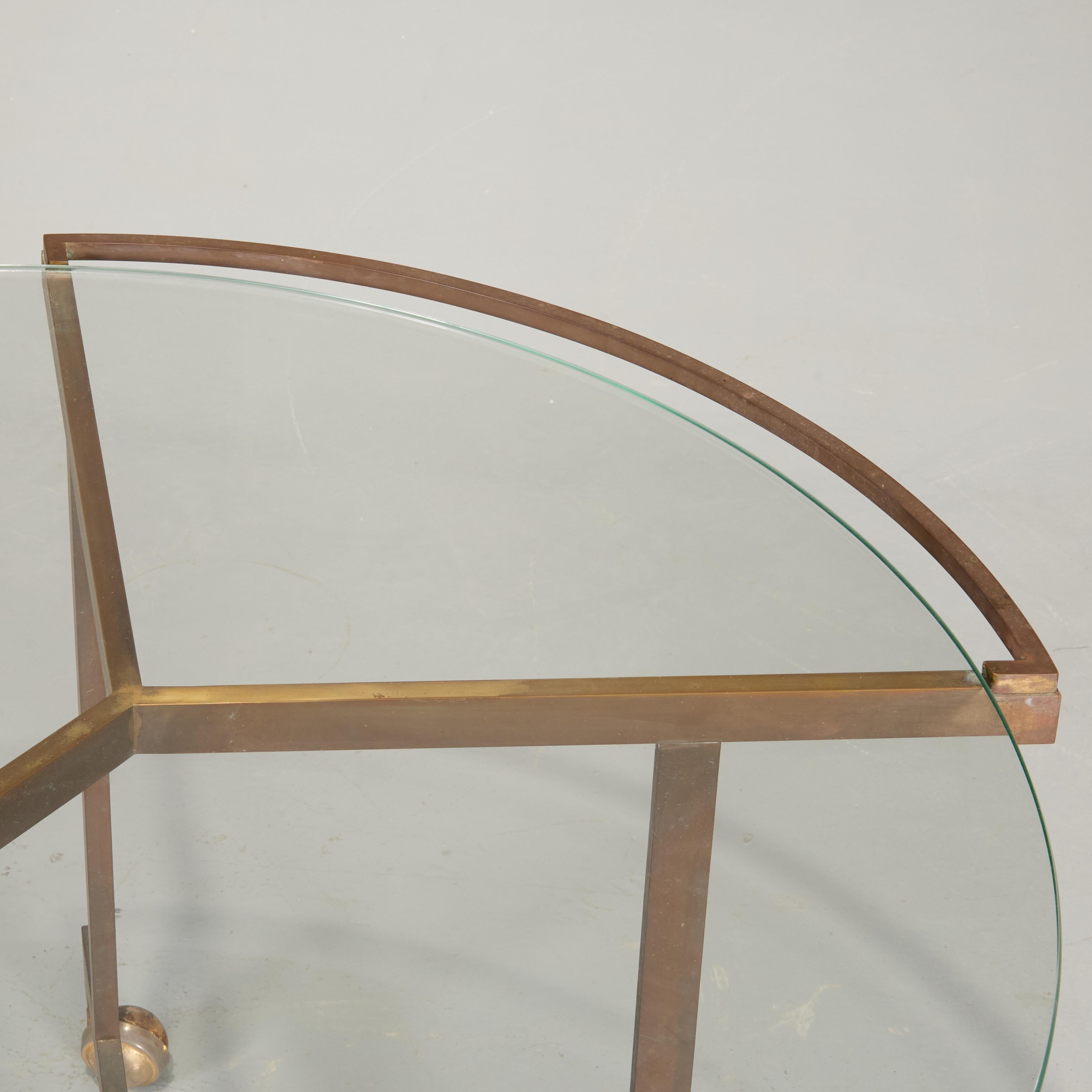 Chic and rare brass table with glass top. Raised on casters and with elegant curved handles, this would make a stirking bar or serving table, but can also double as a coffee table. The brass has taken on a lovely bronzed patina.