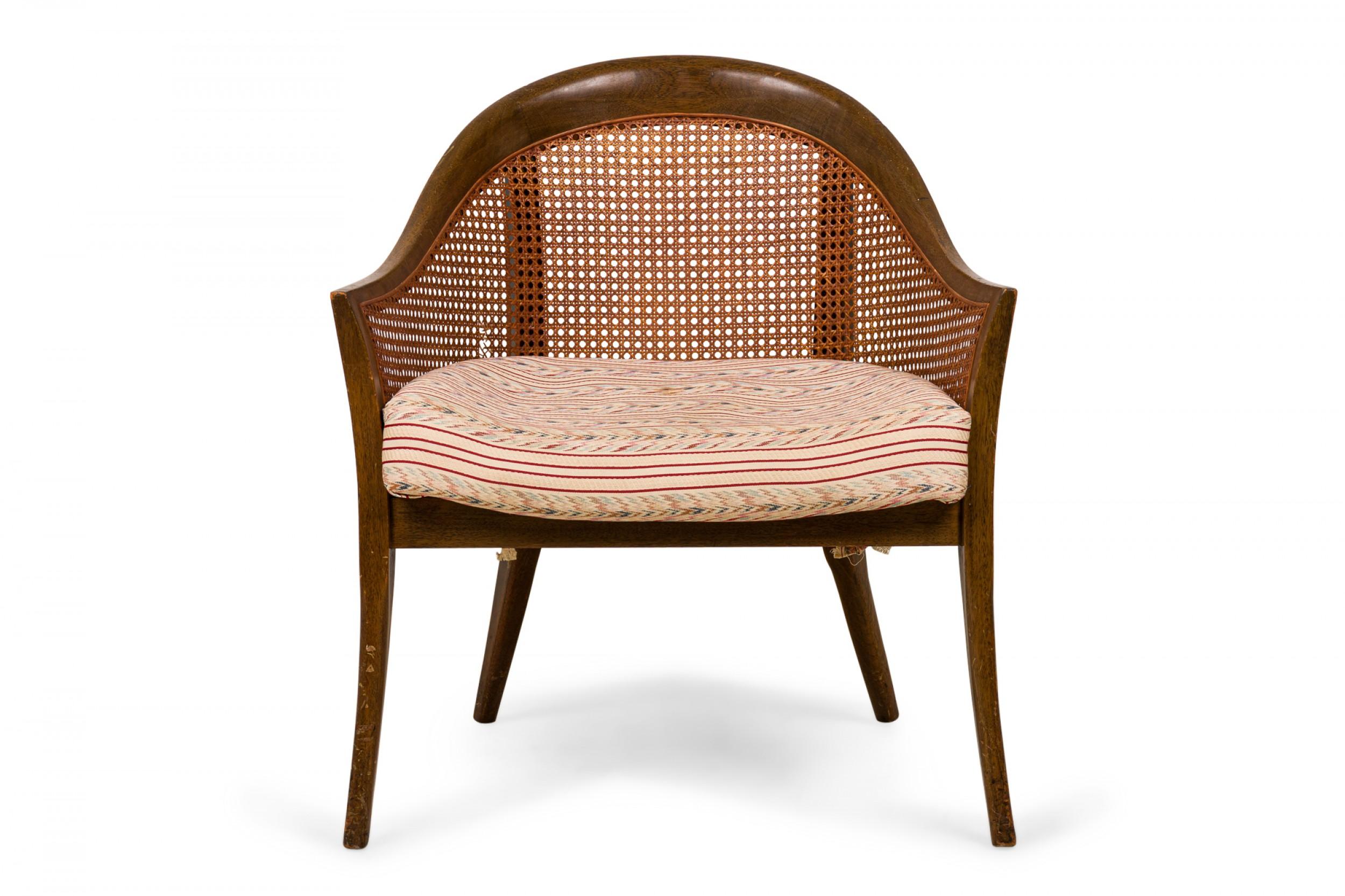 American mid-century armchair with a curved wood frame, caned sides and back, and a multi-colored striped seat cushion, resting on four tapered wooden legs. (HARVEY PROBBER)(Similar chair: DUF0550)