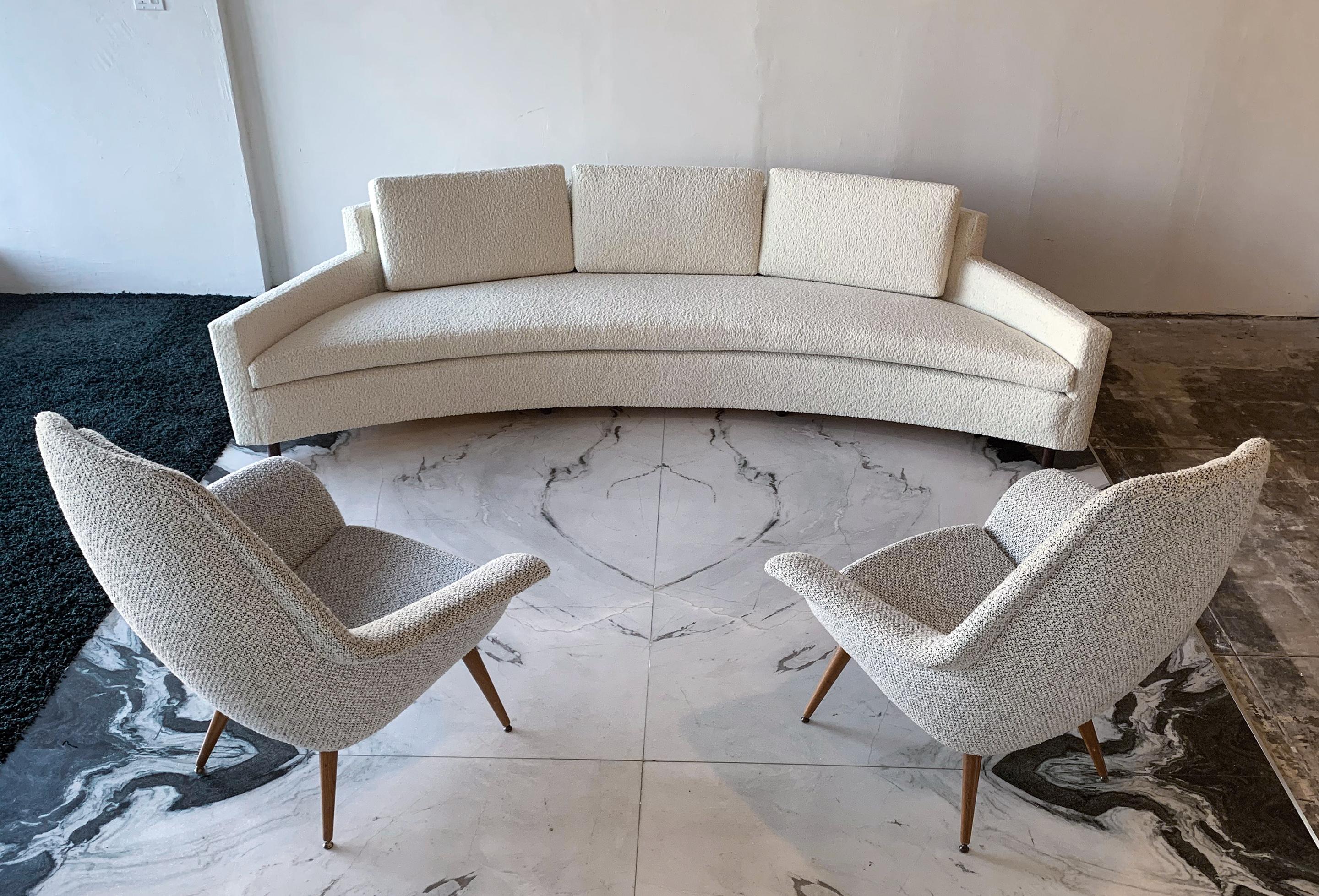 This sofa is simply stunning. A rare 1960s Harvey Probber curved sofa that has been expertly reupholstered in sumptuous heavy bouclé, this curved sofa is truly the pinnacle of clean, modern design. The sofa has a crescent / curved body with walnut