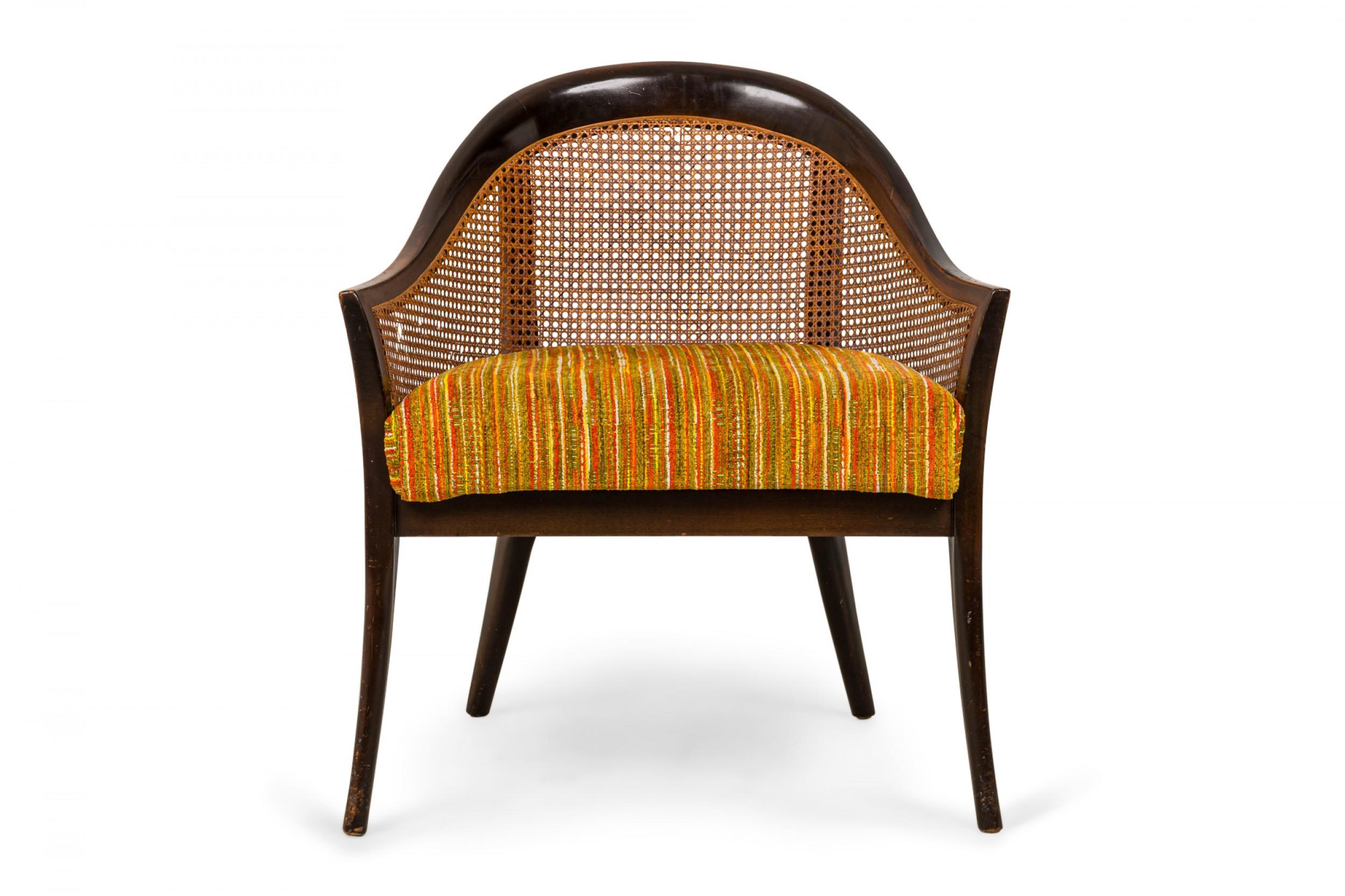 American mid-century armchair with a curved dark wood frame, caned sides and back, and a multi-colored striped seat cushion, resting on four tapered wooden legs. (HARVEY PROBBER)(Similar chair: DUF0551)