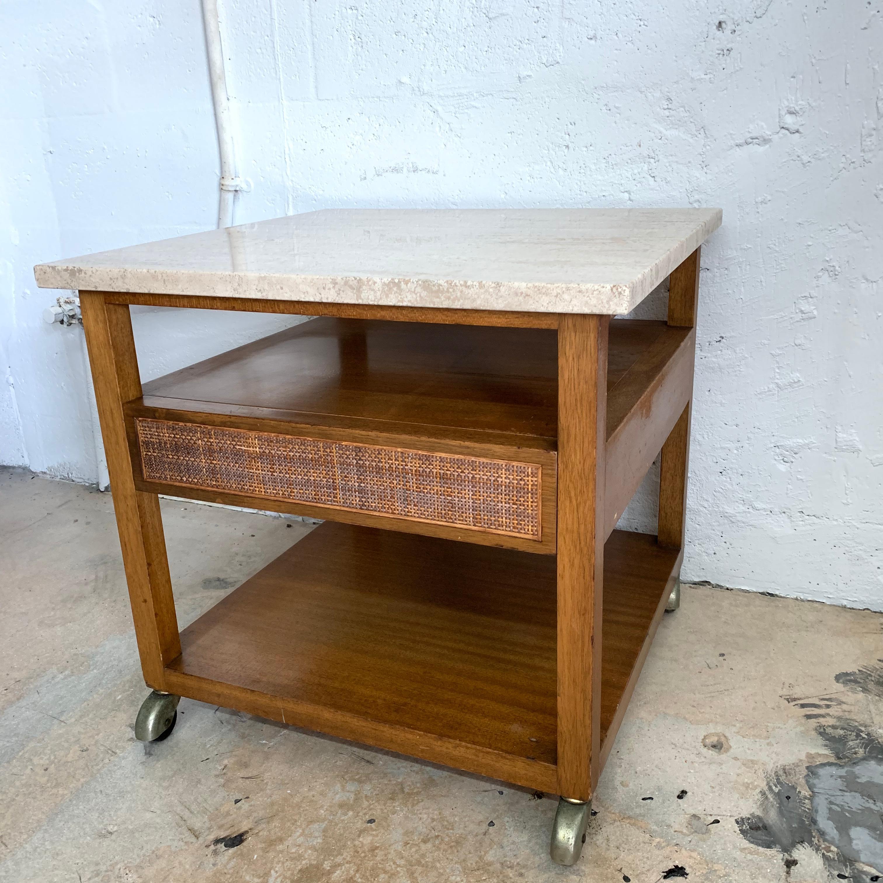 Side or end table rendered in walnut with a travertine top and inset can drawer with brass castors, designed by Harvey Probber, signed.