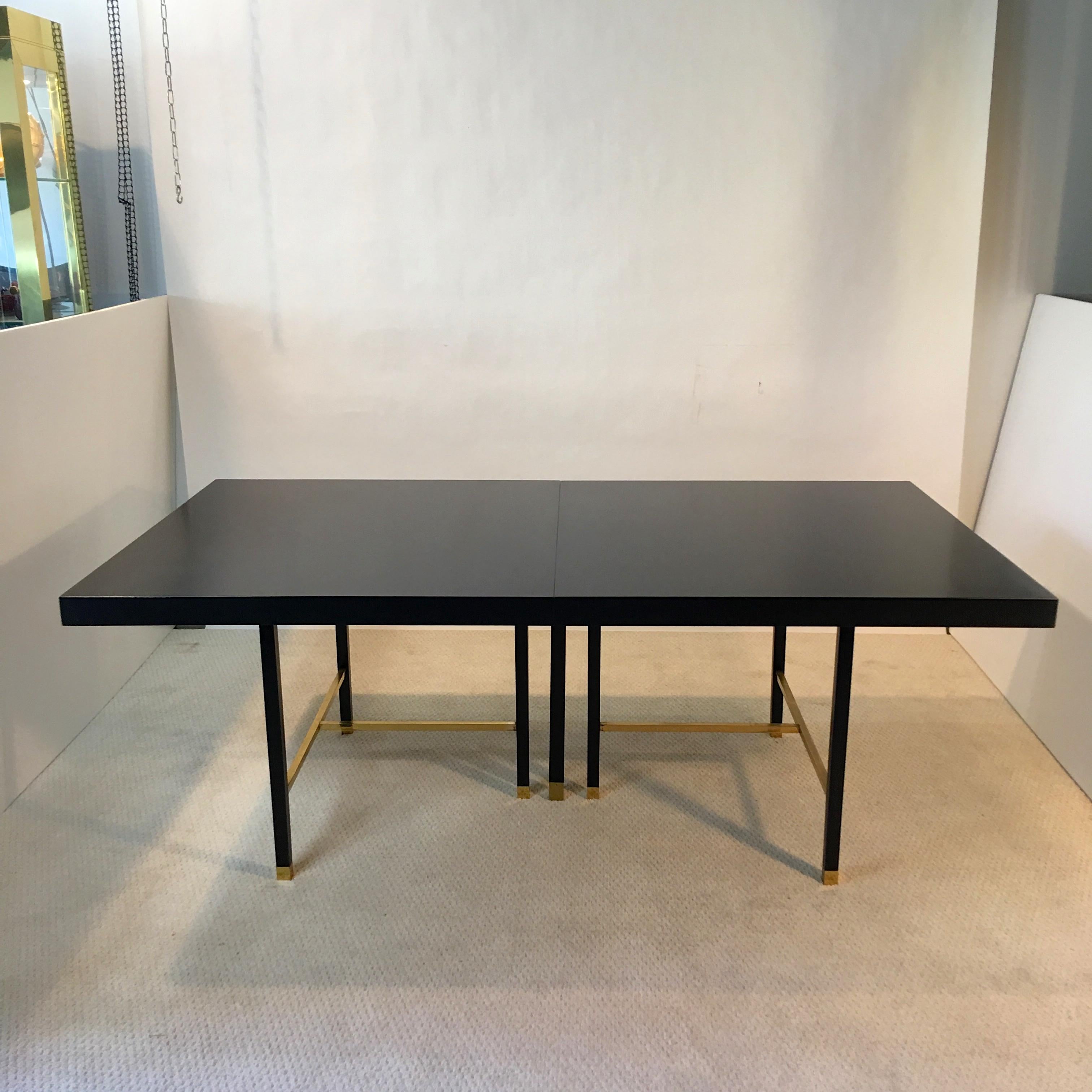 Magnificent minimalist design on a grand scale, ebonized mahogany dining table designed and produced by Harvey Probber, circa 1968 with solid brass square bar cross-stretchers and square leg sabots on seven legs, creating a striking profile both