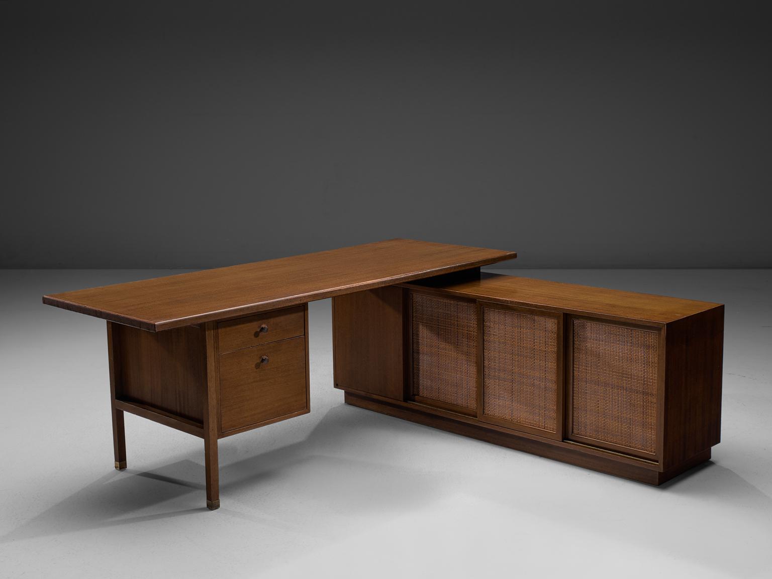Harvey Probber, corner desk, mahogany, rattan and brass, United States, 1950s.

A beautiful Harvey Probber two-piece desk unit including several storage units. The desk surfaces two drawers, and is combined with, but not attached to, a storage