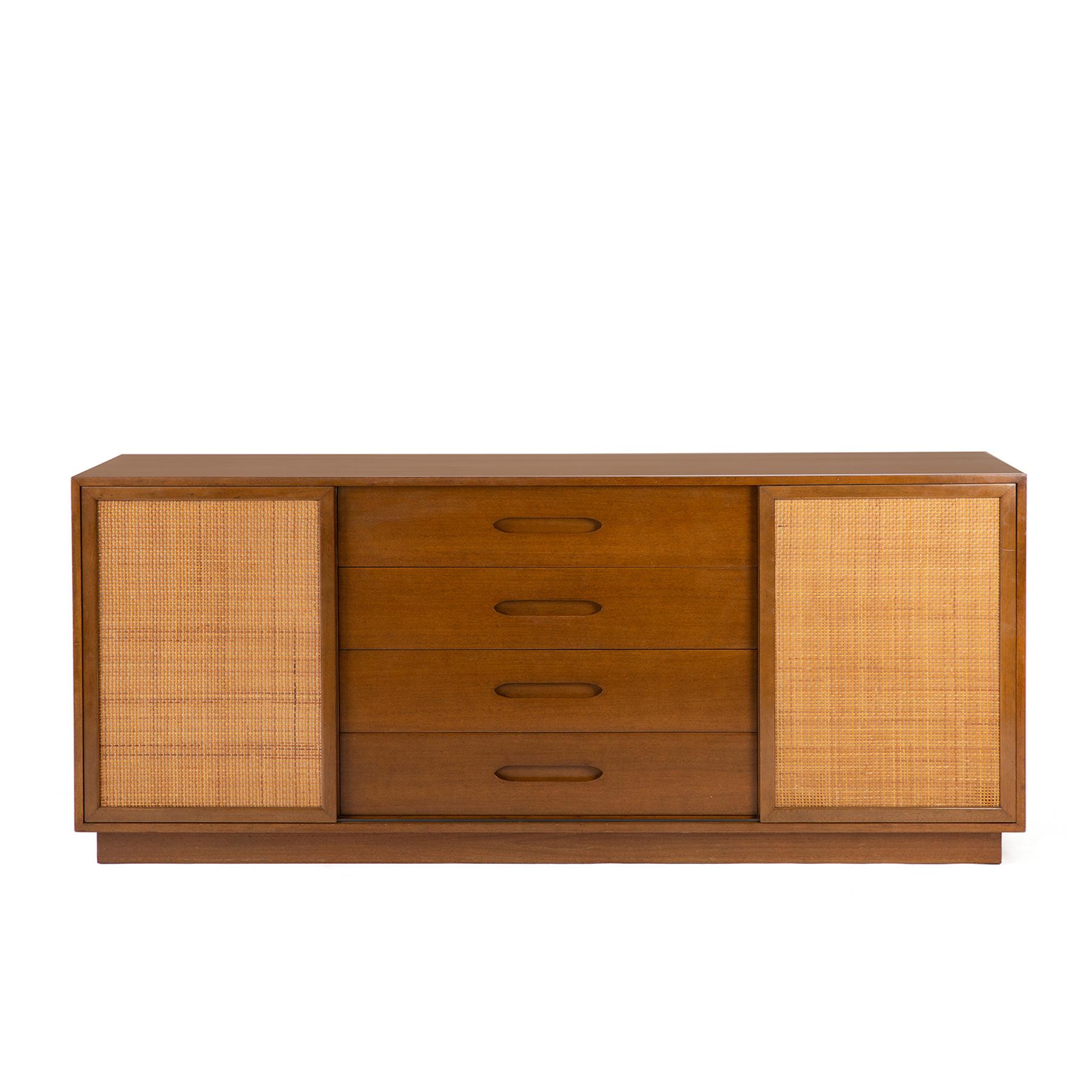 Stately early 1960s sideboard in mahogany by Harvey Probber. This all original chest features four center drawers and two sliding doors with inset caning. The interior has white lacquered drawers on one side and pullout / pull-out shelves on the