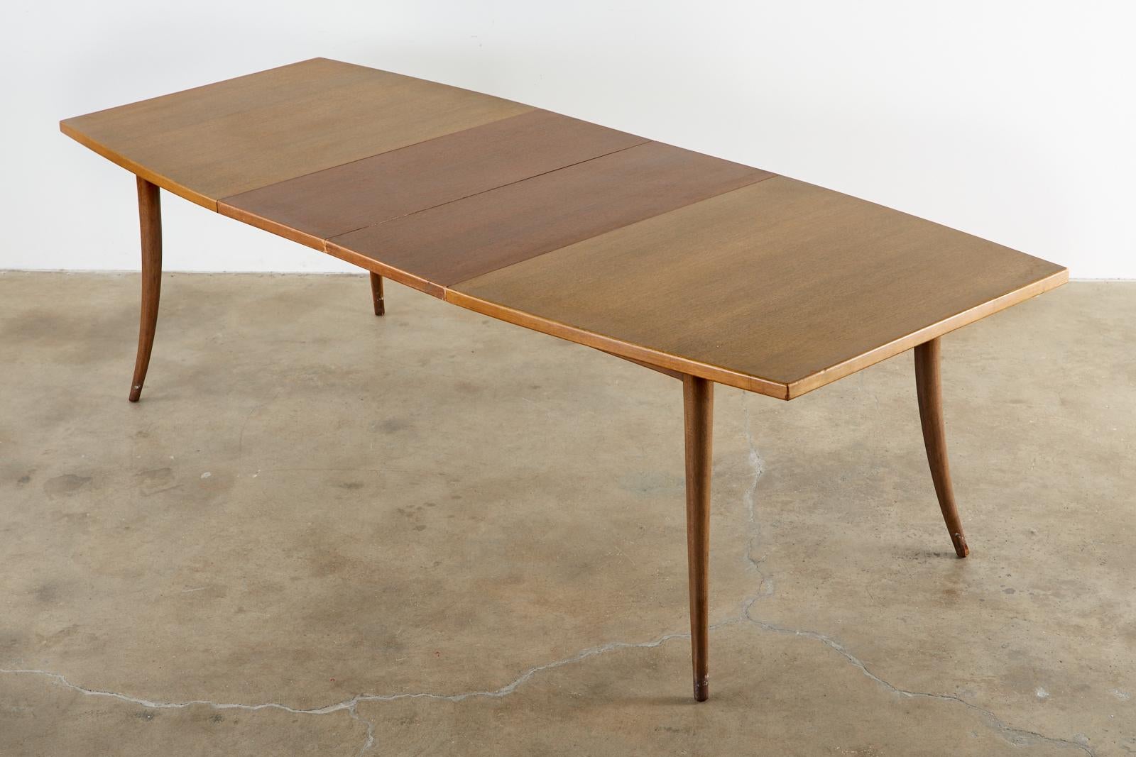 Stylish Mid-Century Modern dining table designed by Harvey Probber featuring two 16 inch extending leaves for a total of 98 inches. The iconic table has sabre formed legs with a dramatic profile and tapered design. Solid and sturdy with a 66 inch