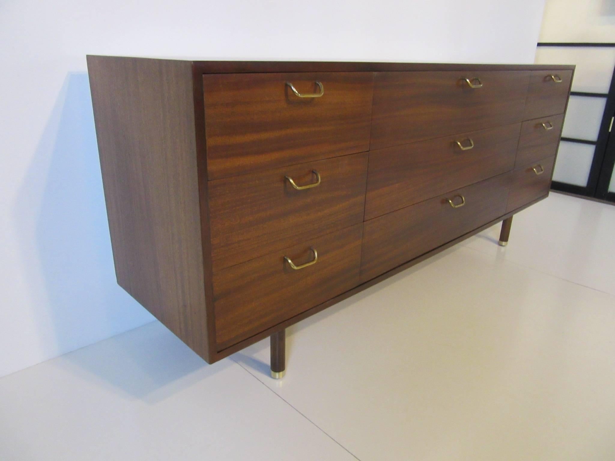 A mahogany nine-drawer dresser chest with solid curved brass pulls and foot caps to the legs the top middle drawer having dividers. Wonderful graining to the wood gives the piece a rich look, retains the manufactures tag 