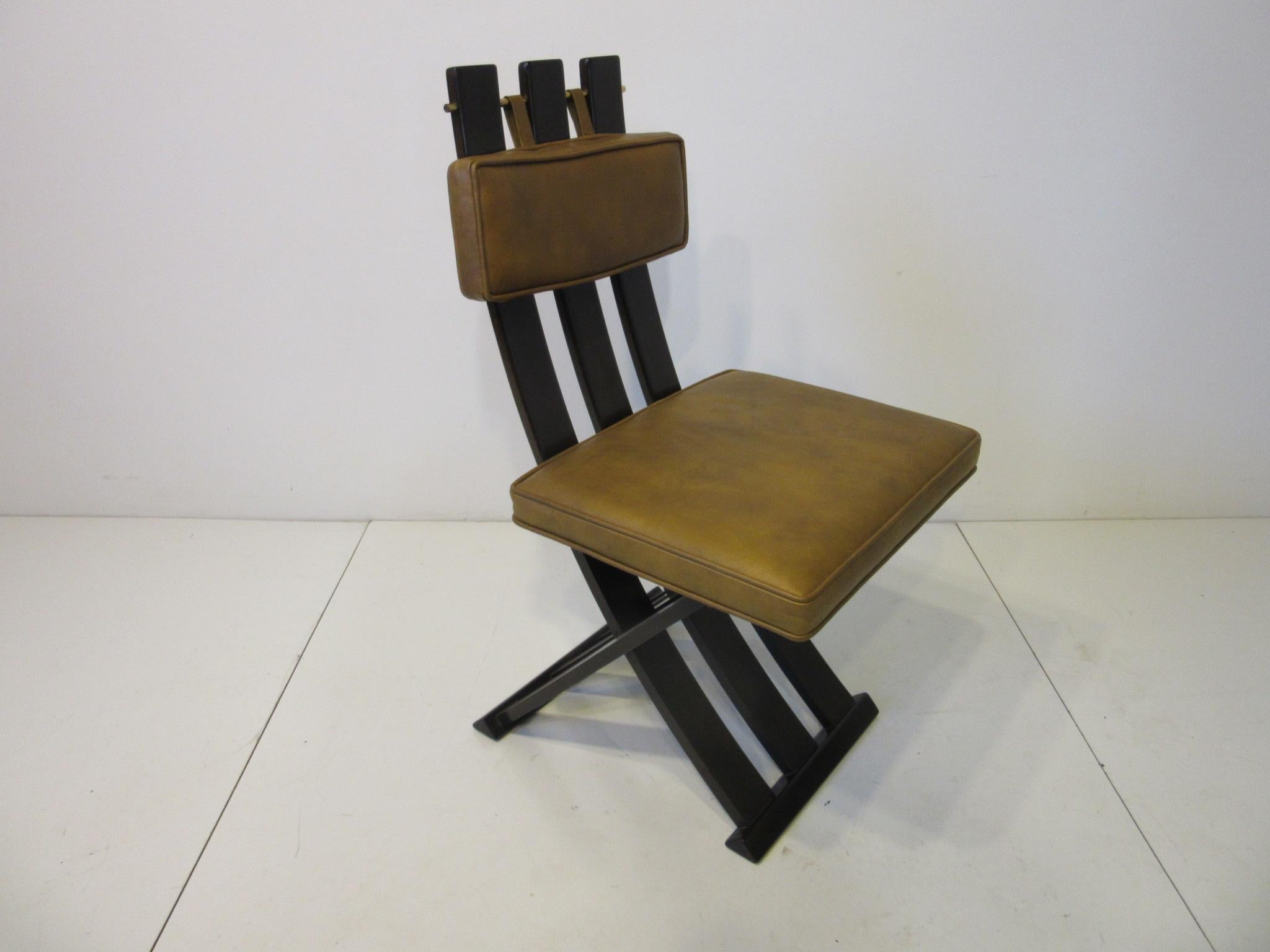 A set of four ebonized mahogany framed X chairs having leatherette back and bottom cushions with brass rod detail holding the slats and cushion. A sophisticated design that is well crafted and of high quality in the manner of Dunbar and Widdicomb,