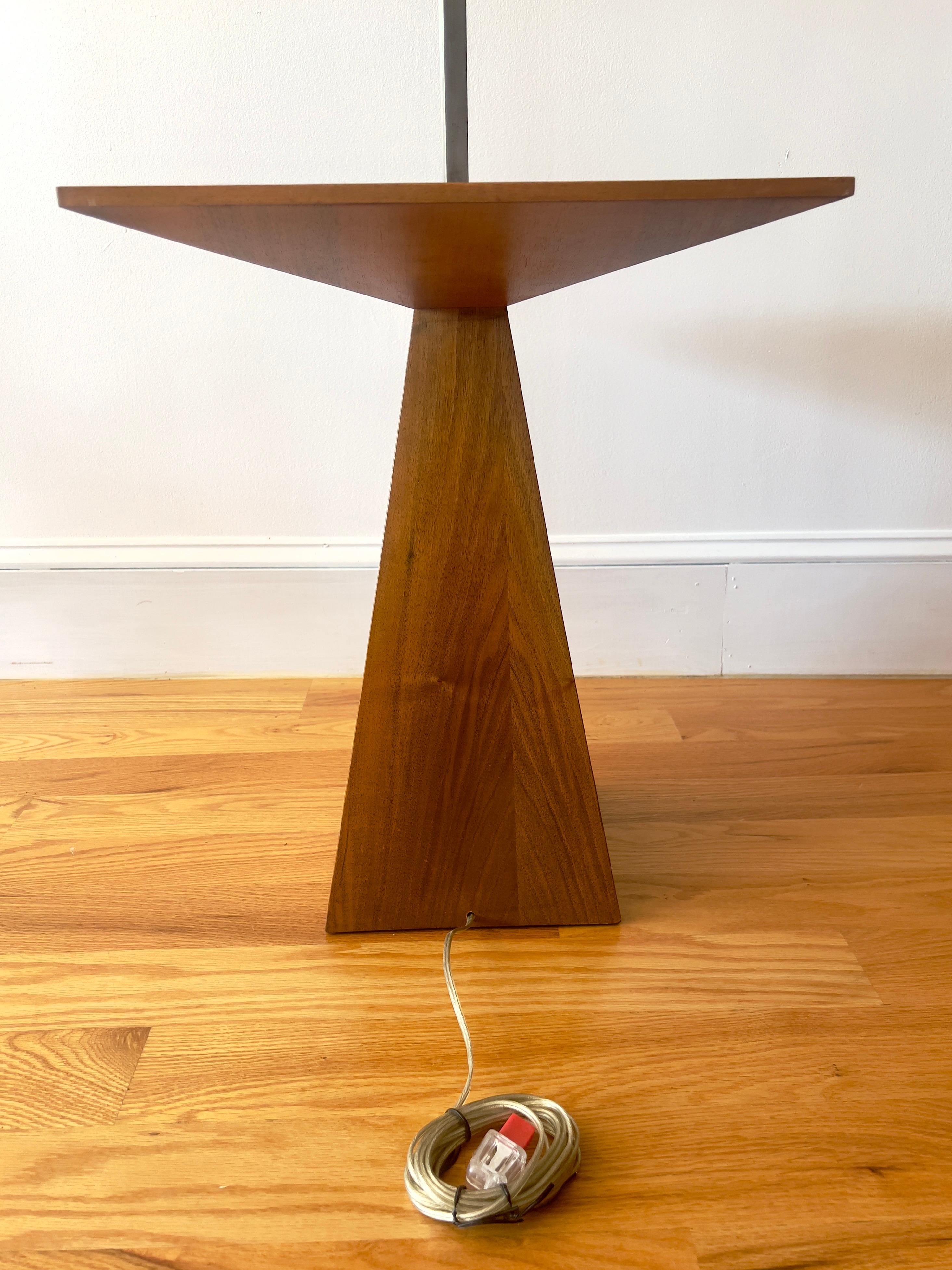 Una lampada da terra di metà secolo di Harvey Probber con tavolino integrato, che unisce una forma scultorea a una funzionalità senza tempo. La base geometrica in noce è sormontata da una superficie impiallacciata in tinta con il libro, che mette in