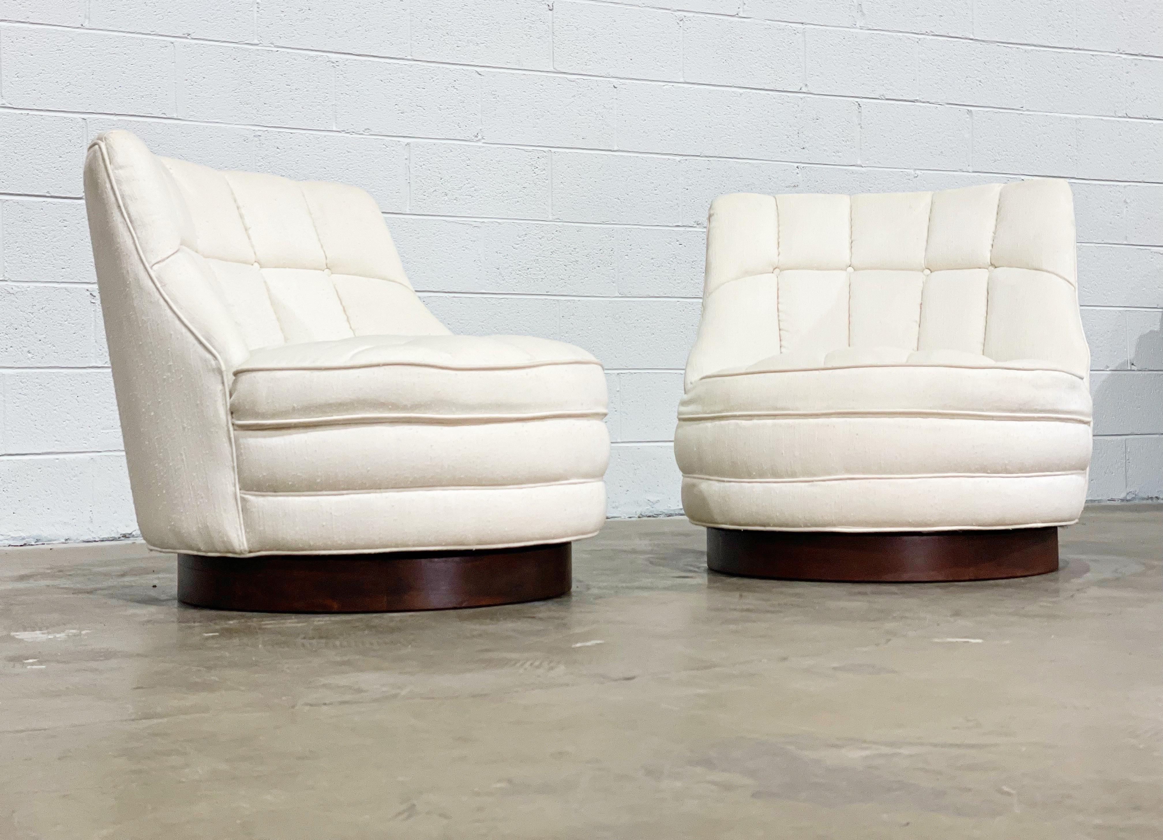 Pair of stunning Mid-Century Modern tufted swivel slipper style barrel chairs with walnut plinth bases by Harvey Probber. Boucle style nubby white upholstery is in good condition and presents well, but does show wear. New upholstery is recommended.