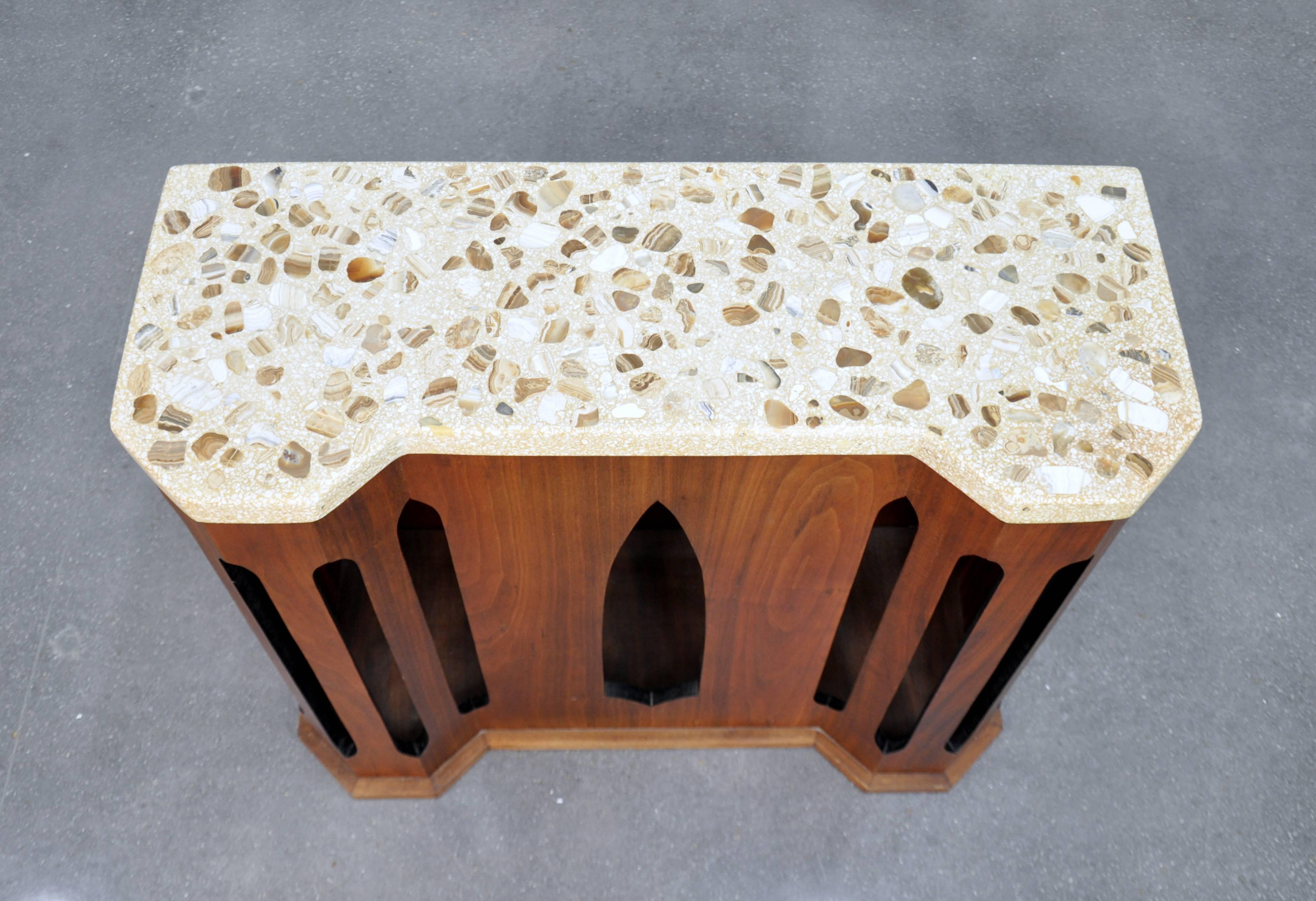 A rare Mid-Century Modern console, foyer or entry table designed by Harvey Probber, dating from the early 1960s. It features a shaped terrazzo top inlaid with onyx and marble chips over a sculptural walnut base of Moroccan inspiration. The onyx