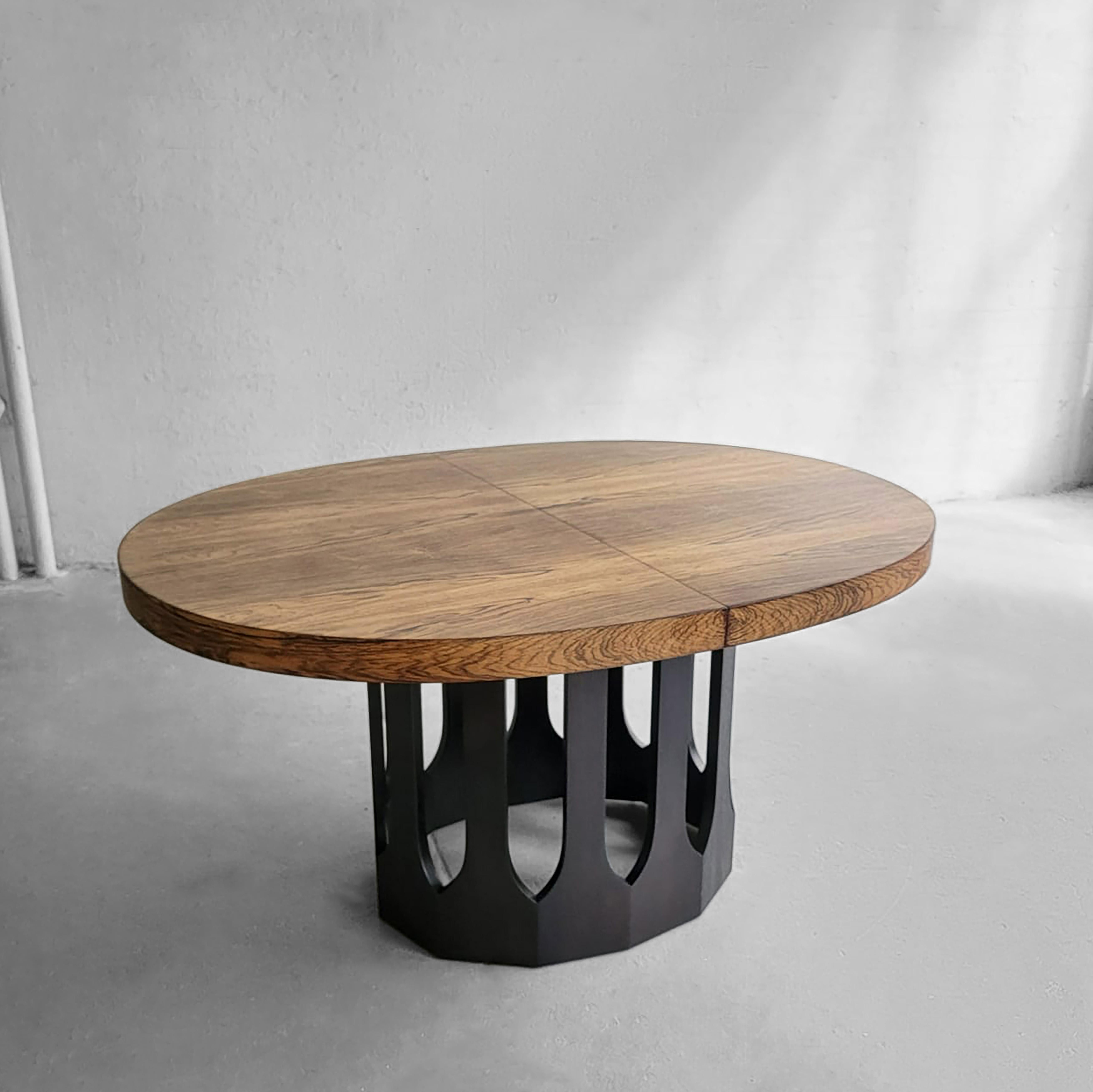 Mid-Century Modern, extension dining table by Harvey Probber features a 2.5 inch thick, oval rosewood top with an ebonized mahogany base with Moroccan cut-out detail. The table extends from 56 - 88 inches with two 16 inch leaves. The chair clearance