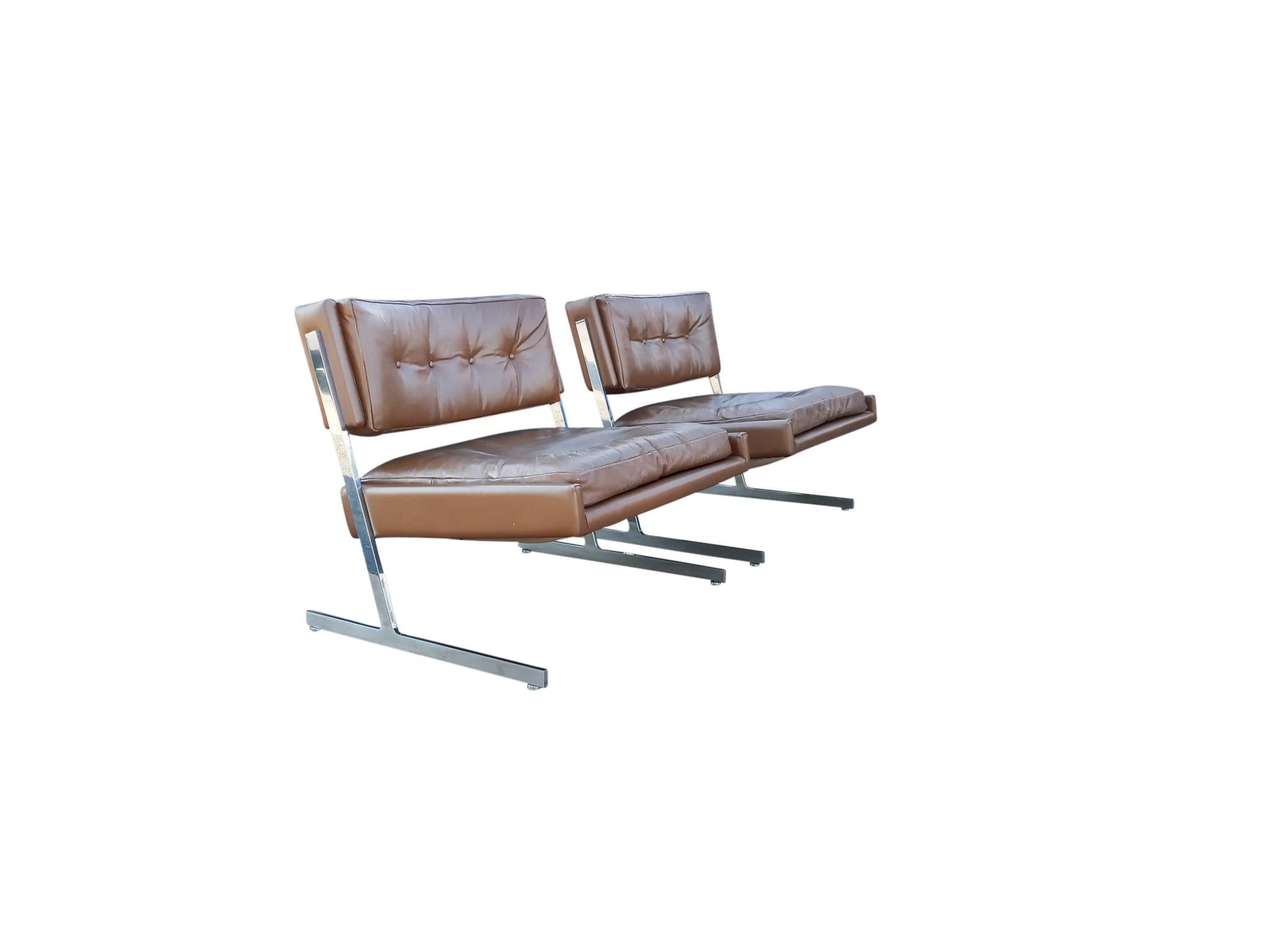 Cette élégante paire de chaises longues Probber présente un profil dynamique obtenu grâce à l'utilisation d'un siège cantonné soutenu par des cadres en acier inoxydable poli. Le cuir origina marron chocolat est capitonné. Et les cadres en acier