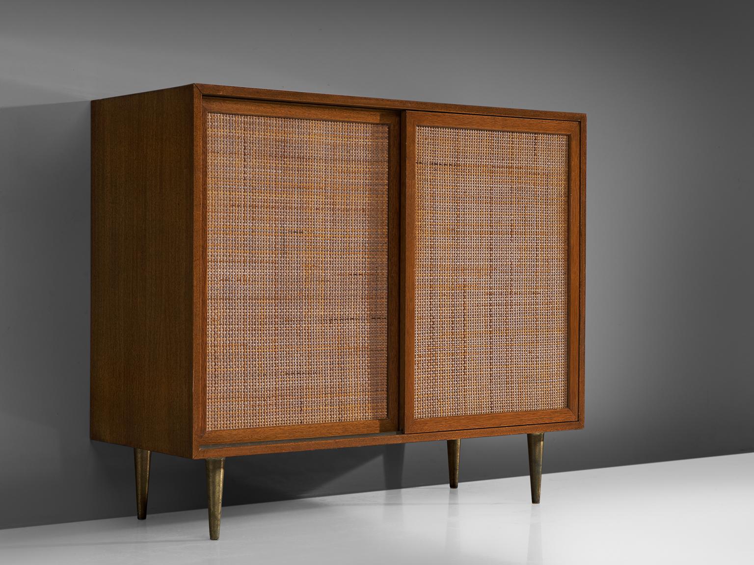Harvey Probber, cabinet, rattan, mahogany and brass, United States, 1950s. 

This piece by Probber features a mahogany body. The mahogany functions as a frame for the rattan doors. The cabinet features two shelves and rests on four delicate