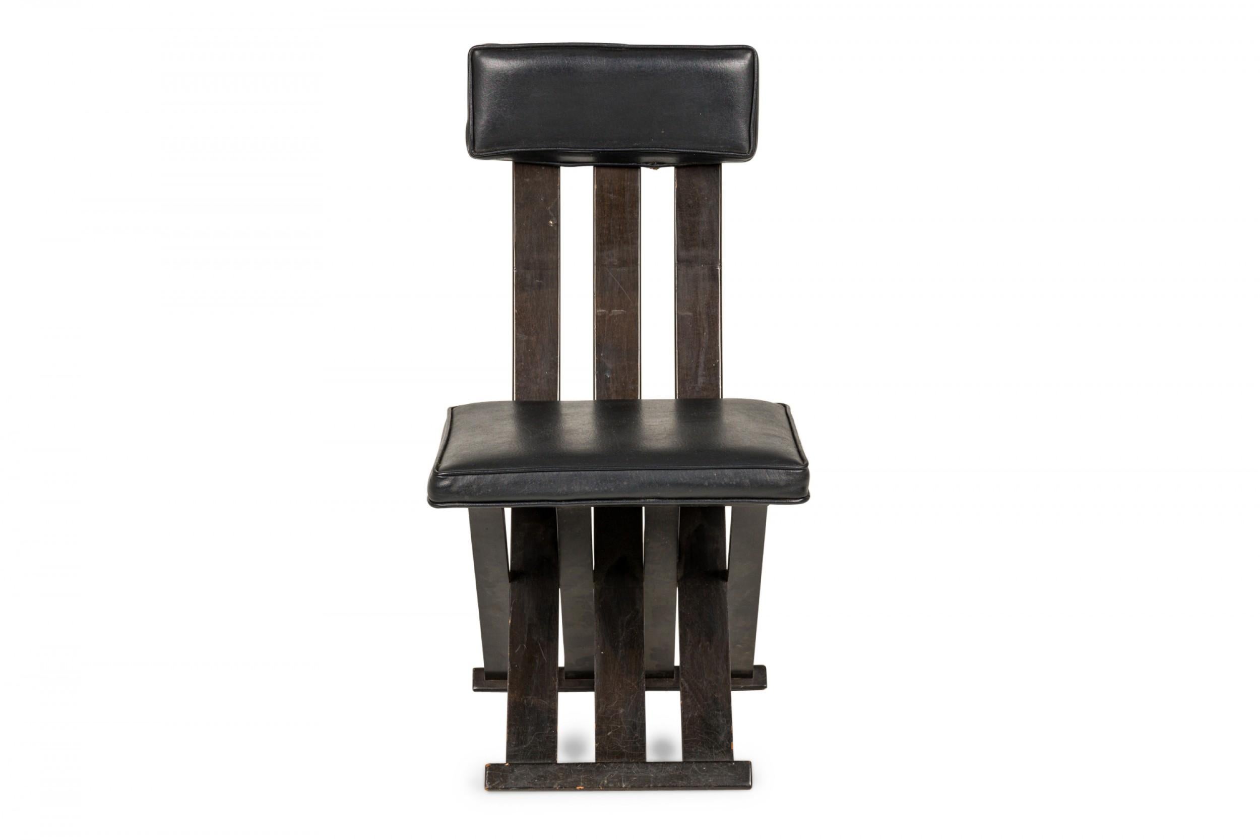 American Mid-Century scissor form dining / side chair with an ebonized wooden frame with a narrow back comprised of three vertical slats, with a black leather upholstered seat and small rectangular back cushion, resting on a three slat scissor-form
