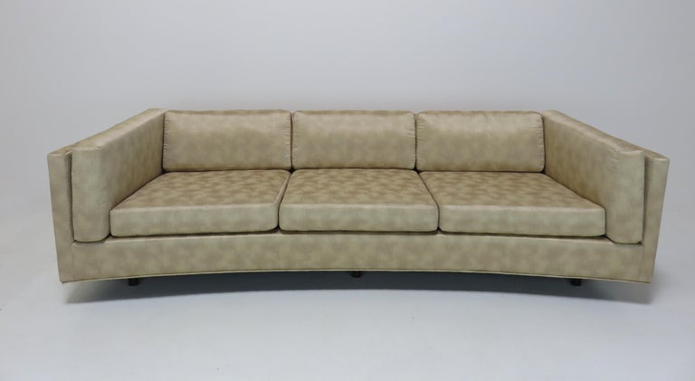 A three-seat sofa by Harvey Probber. Curved front. Loose cushions on the seat, back and sides. Sofa sits on 6 wooden feet.
