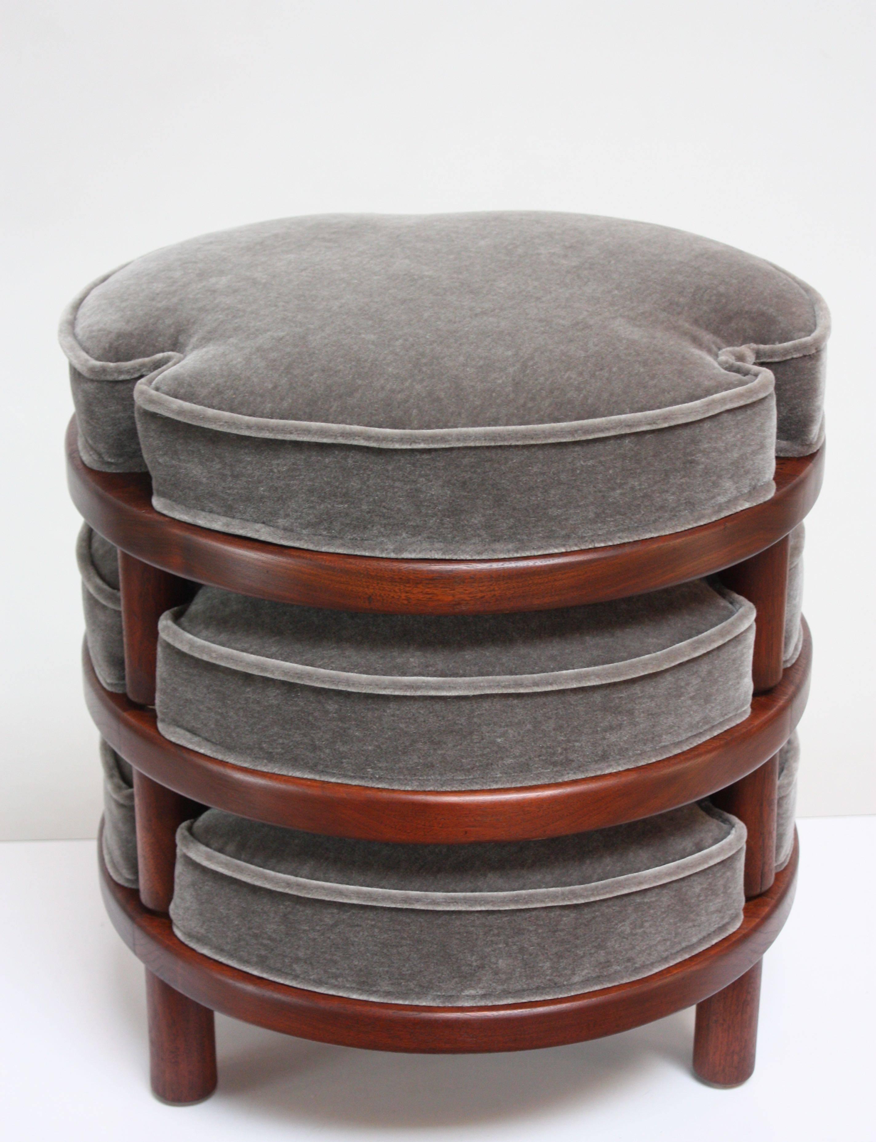 Luxe set of three stacking ottomans in mahogany with new foam and light charcoal mohair cushions. Three 'cut-out' corners
per cushion in which the cylindrical feet nest.
Frames have been refinished; mohair and foam are new.
Listed height reflects