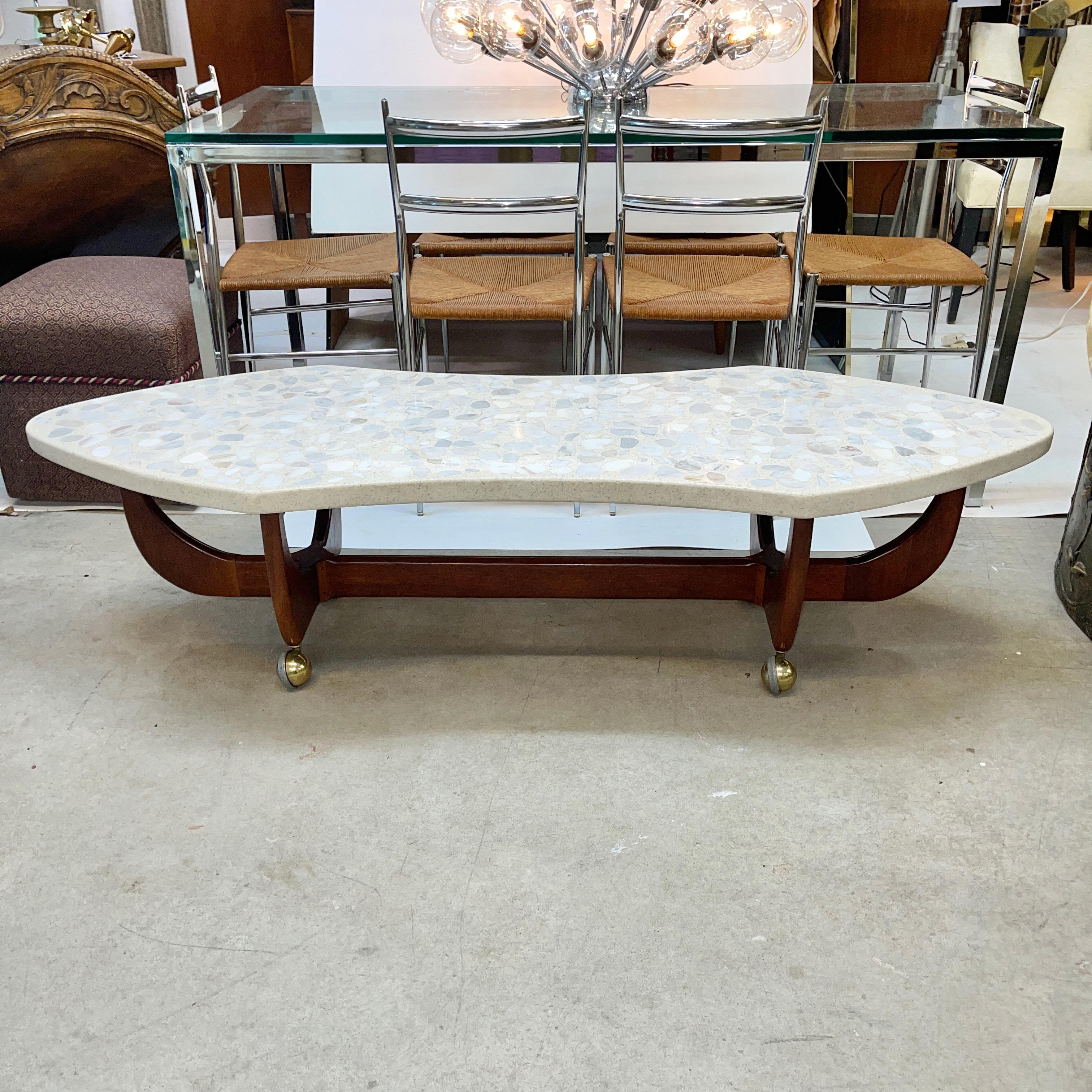 Harvey Probber designed sculptural walnut base cocktail table with a thick terrazzo top shaped somewhere between a surfboard and a cartouche. 
The terrazzo top is affixed the walnut base and appears to have embedded elements of onyx and marble.