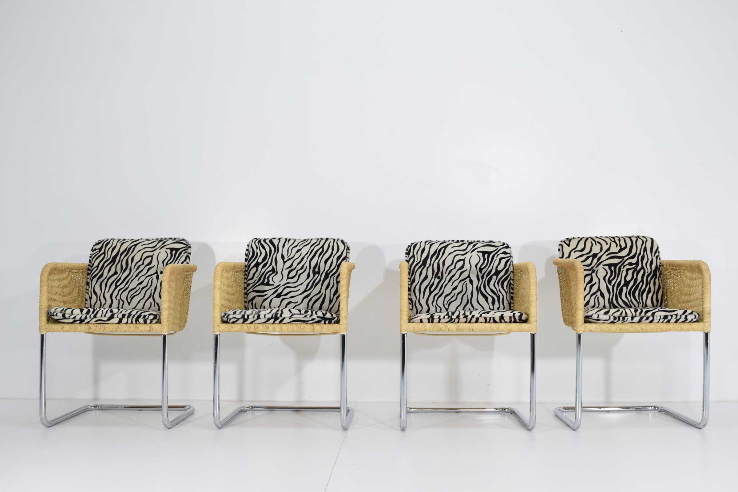 A nice set of four Harvey Probber cantilevered dining chairs. They have a chrome frame, wicker tub seat and zebra hide black and white cushions. Height with cushion is 30.5