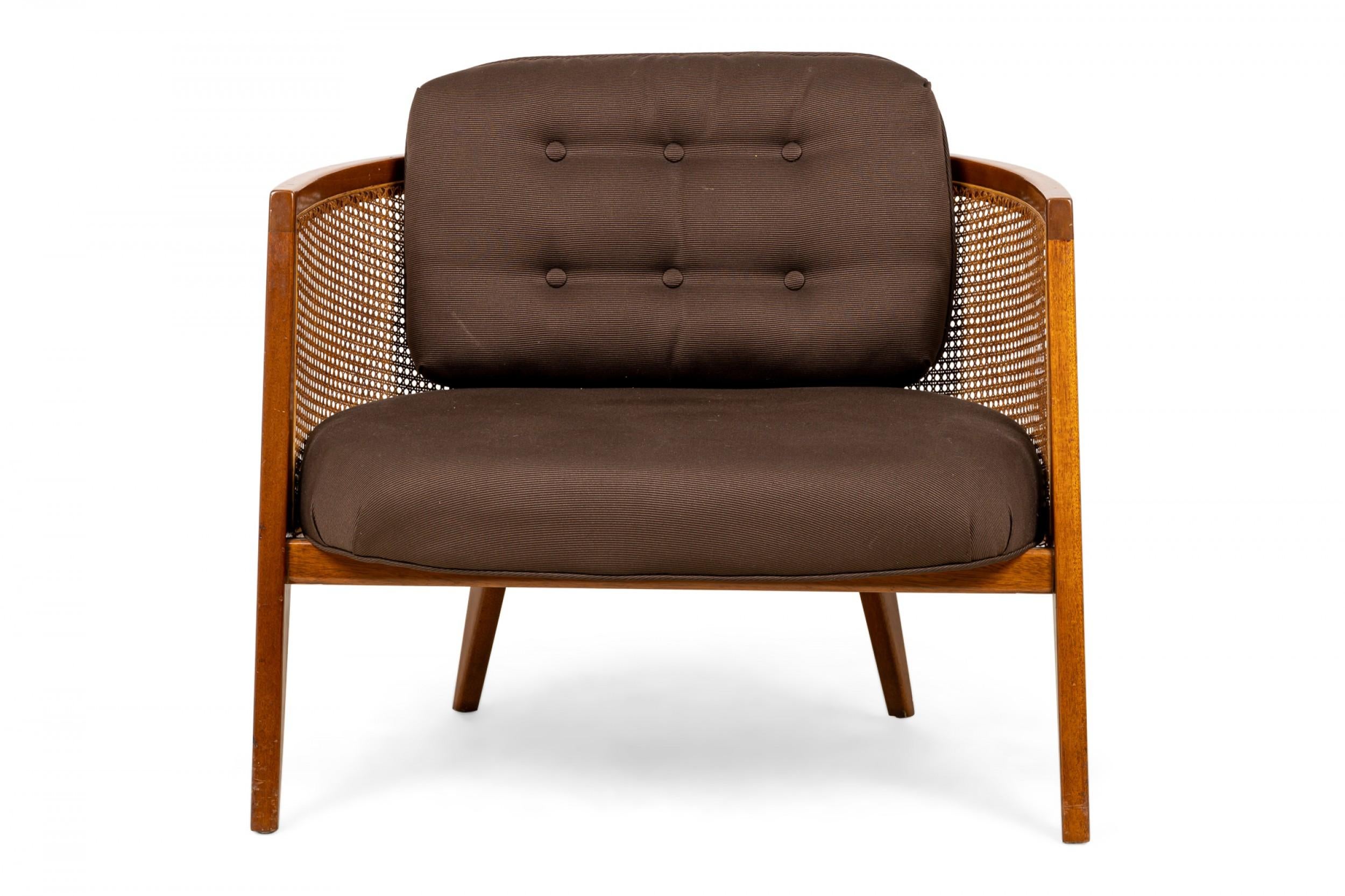 American mid-century hoop form lounge armchair with a curved wooden frame, caned back, seat, and sides, and a dark brown fabric upholstered seat cushion and matching back cushion with button tufted detail, resting on four angled tapered square legs.
