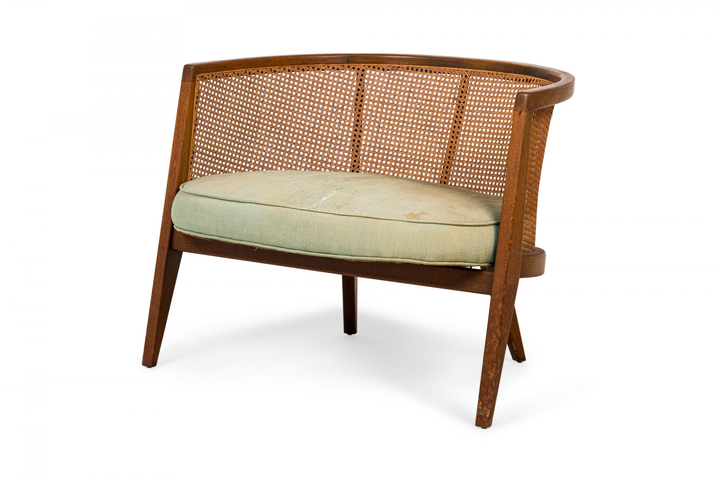 American mid-century hoop form lounge armchair with a curved wooden frame, caned back, seat, and sides, and a light green fabric upholstered seat cushion, resting on four angled tapered square legs. (HARVEY PROBBER)
 