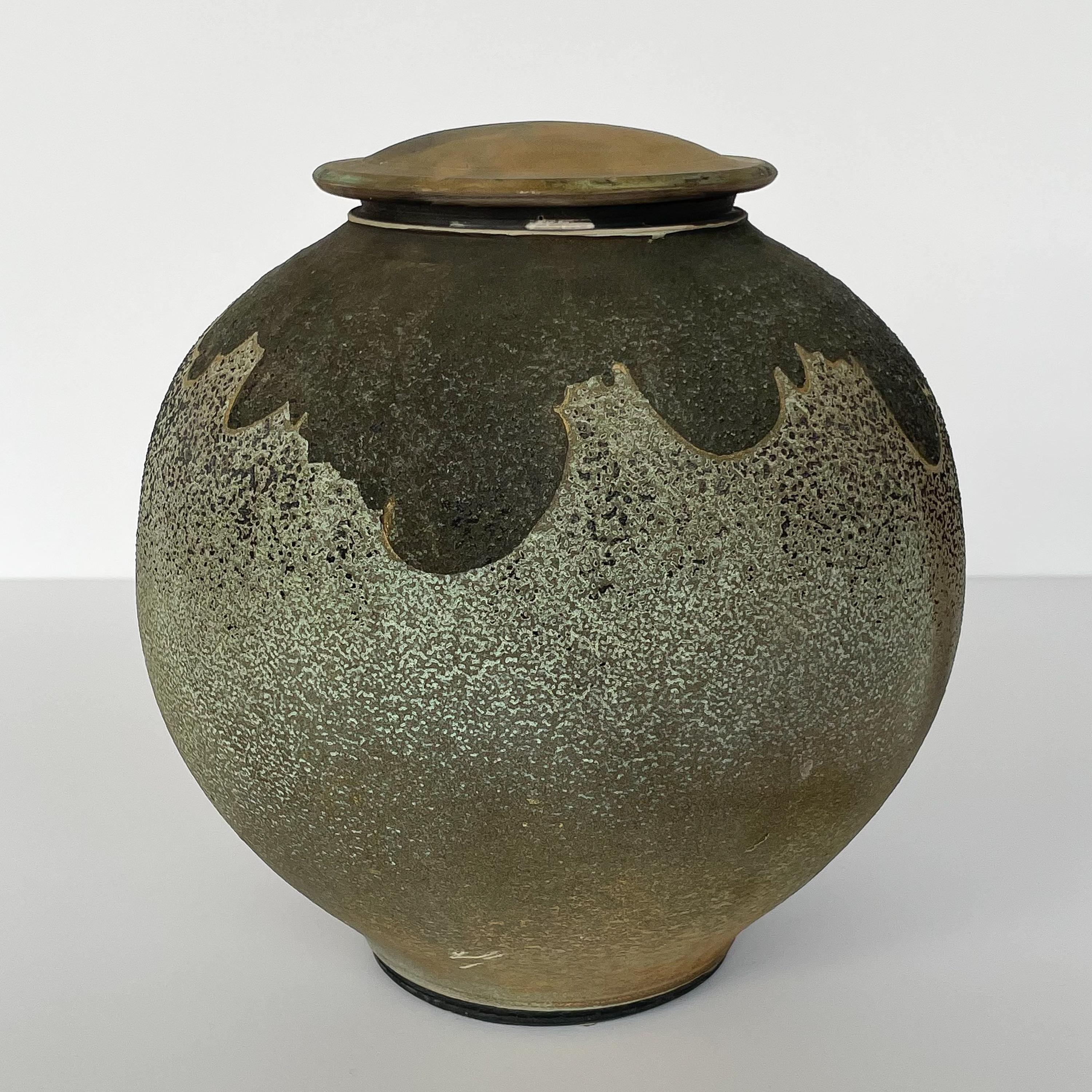 Raku fired lidded stoneware vessel by Harvey Sadow (American, b. 1946), circa 1980s. This hand thrown ceramic jar features a graphic cloud-like abstract design around the opening. Textural raku glaze in pale greens and earthtones. Titled:
