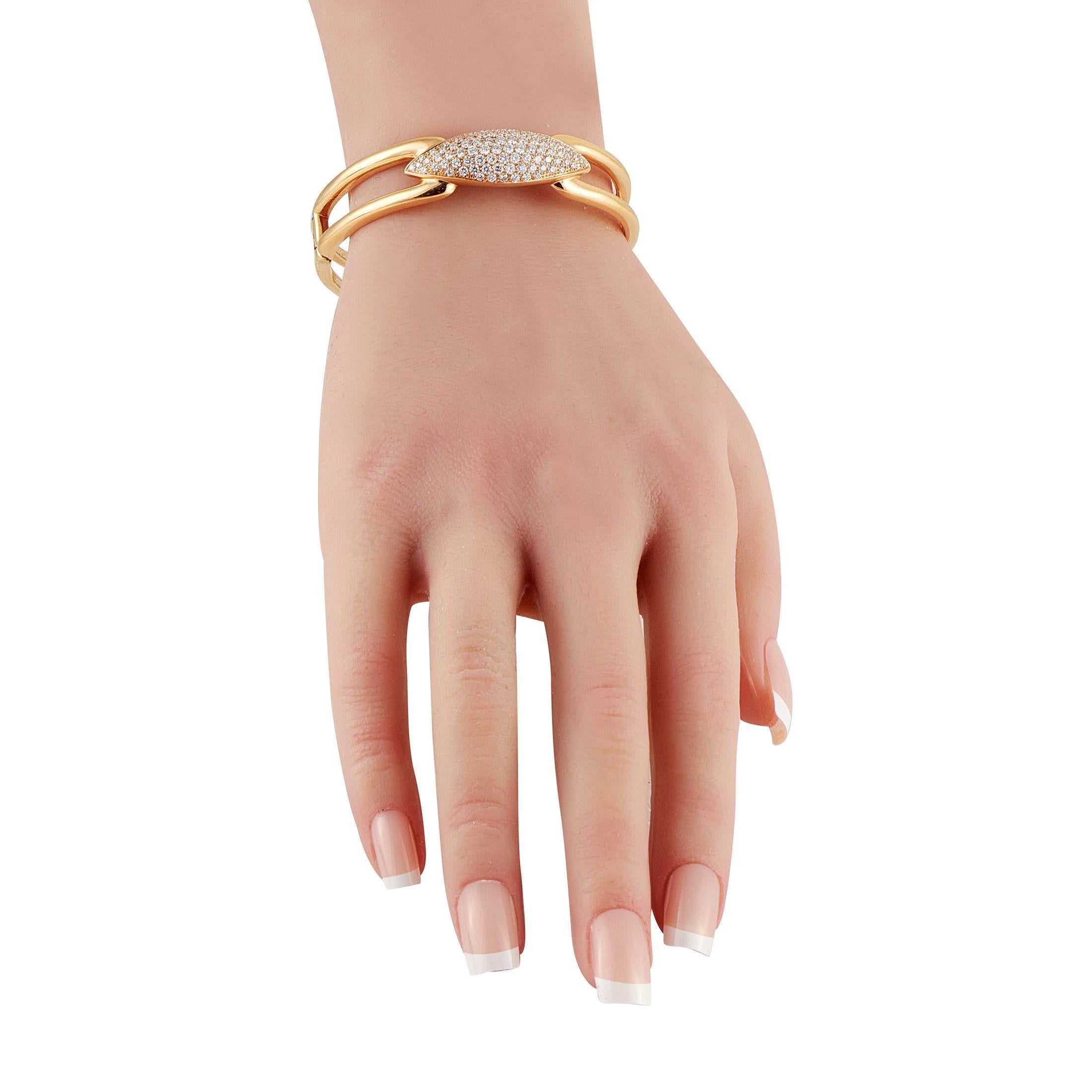 Questo pezzo Hasba attira l'attenzione con la sua silhouette audace e il suo look raffinato. Presenta un design rigido e aperto con finitura lucida. Al centro c'è un'impressionante lunetta a forma di marquise completamente incrostata di delicati