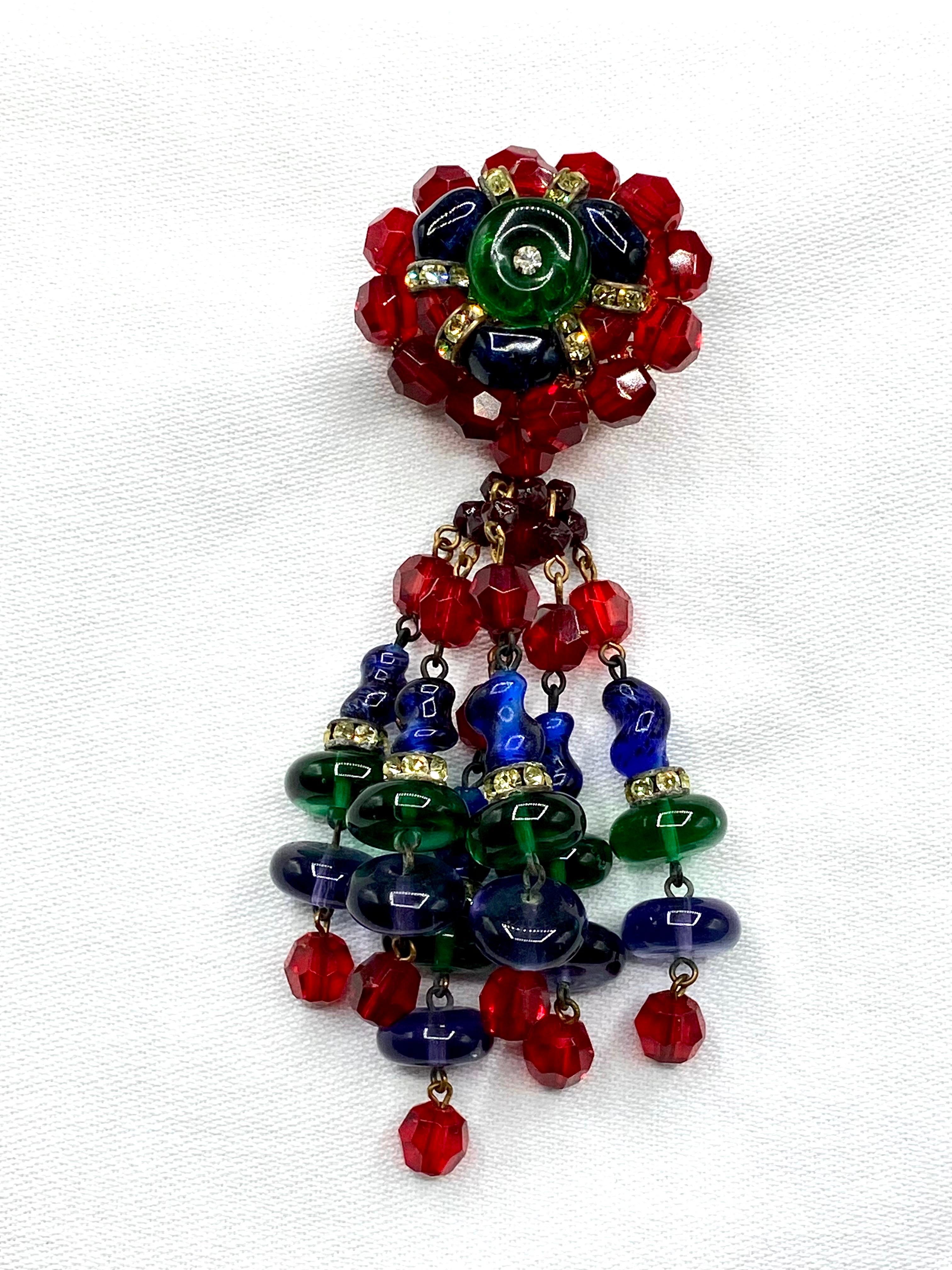 A colorful and fun Hattie Carnegie molded glass and crystal bead tassel brooch from the 1950s. The top oval button piece has a molded green glass donut shape set with a center rhinestone. It is surrounded by a row of molded blue glass beads,
