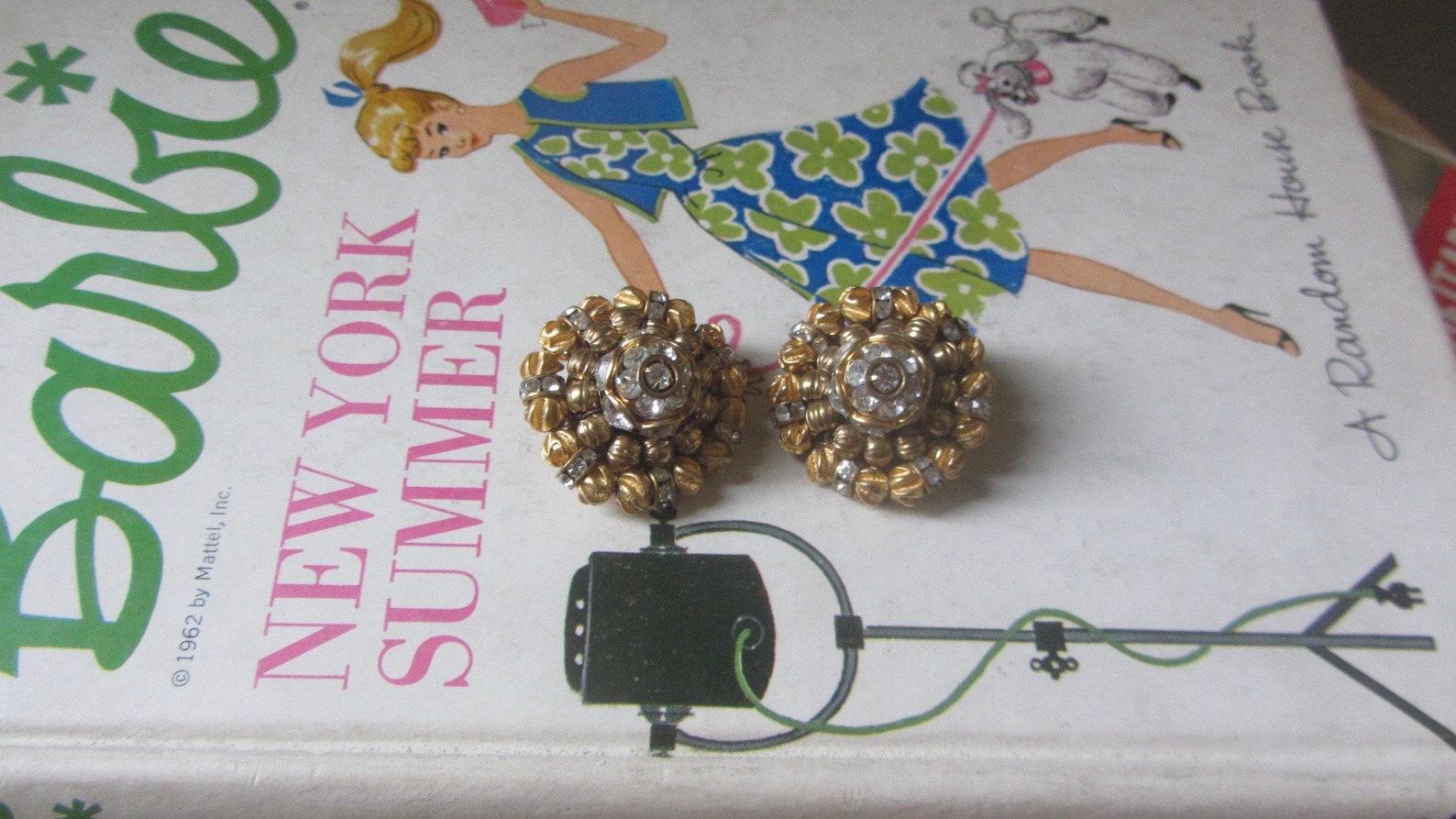 Vintage 1950s gold tone clip-on earrings by Hattie Carnegie. Gorgeous three tier dome shaped earrings are made up of individual brushed gold textured beads and sparkling crystal clear rhinestone rondelles. 

The most amazing earrings!

Marked: