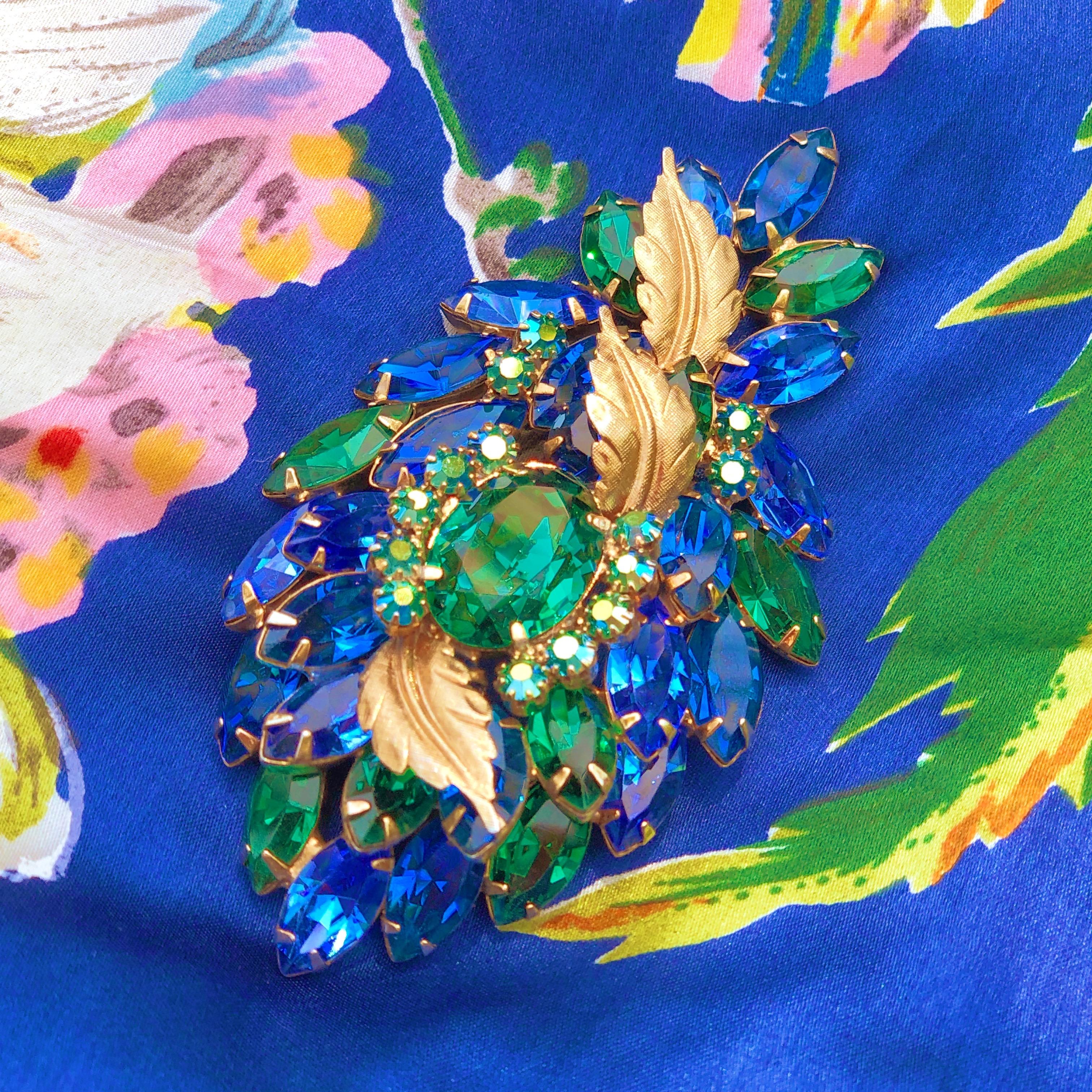 This breathtaking vintage brooch and clip-on earring set by iconic designer Hattie Carnegie is a true treasure from a bygone era!  Reminiscent of peacock feathers, this set is composed of sparkling Emerald green and Sapphire blue colored crystal