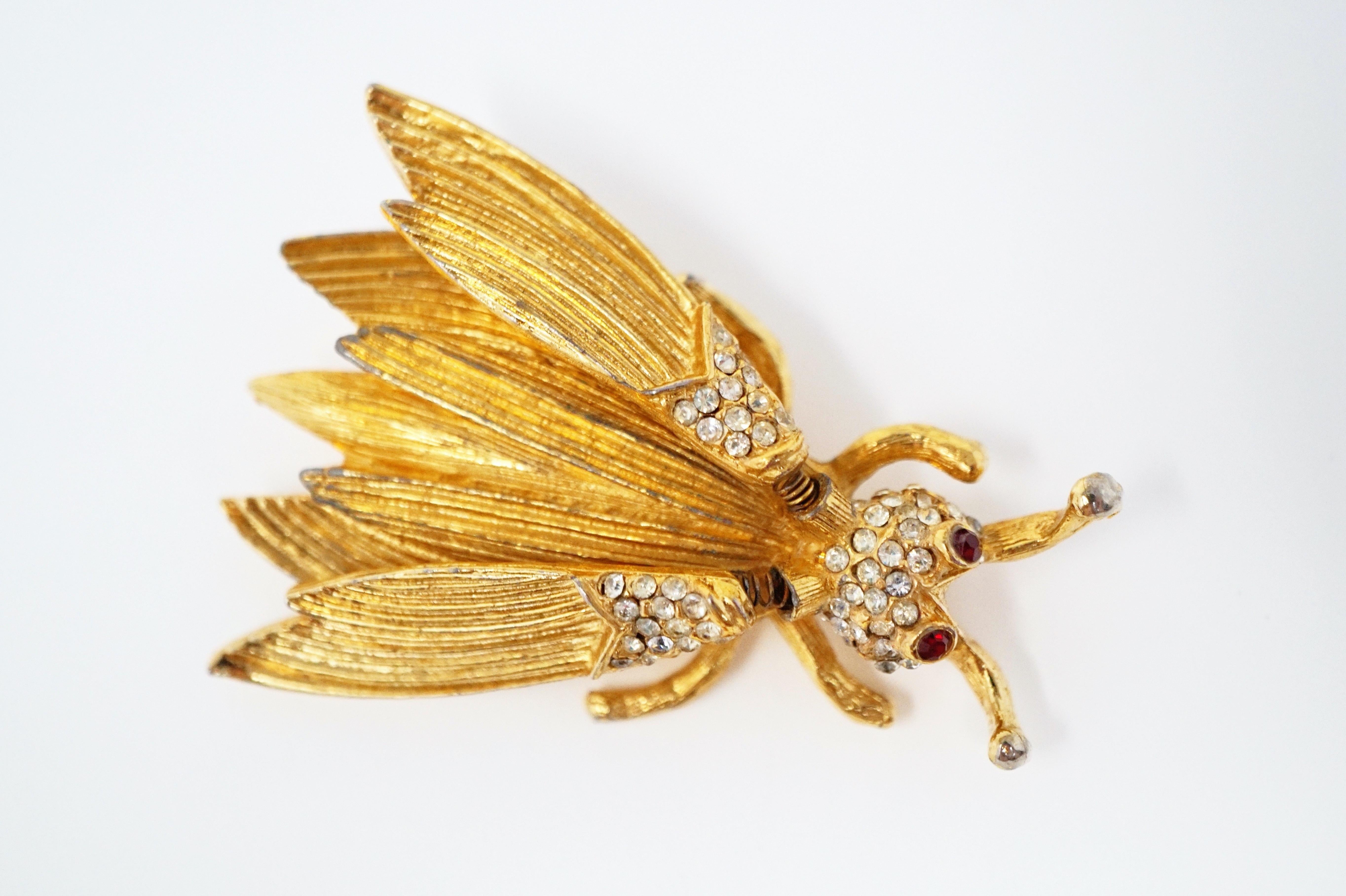 This whimsical insect trembler brooch, attributed to Hattie Carnegie circa 1940s, has wings on tiny springs so that they flutter with every movement.  Covered in gold-plating and crystal rhinestone pavé, this little bug is such a fun and unique