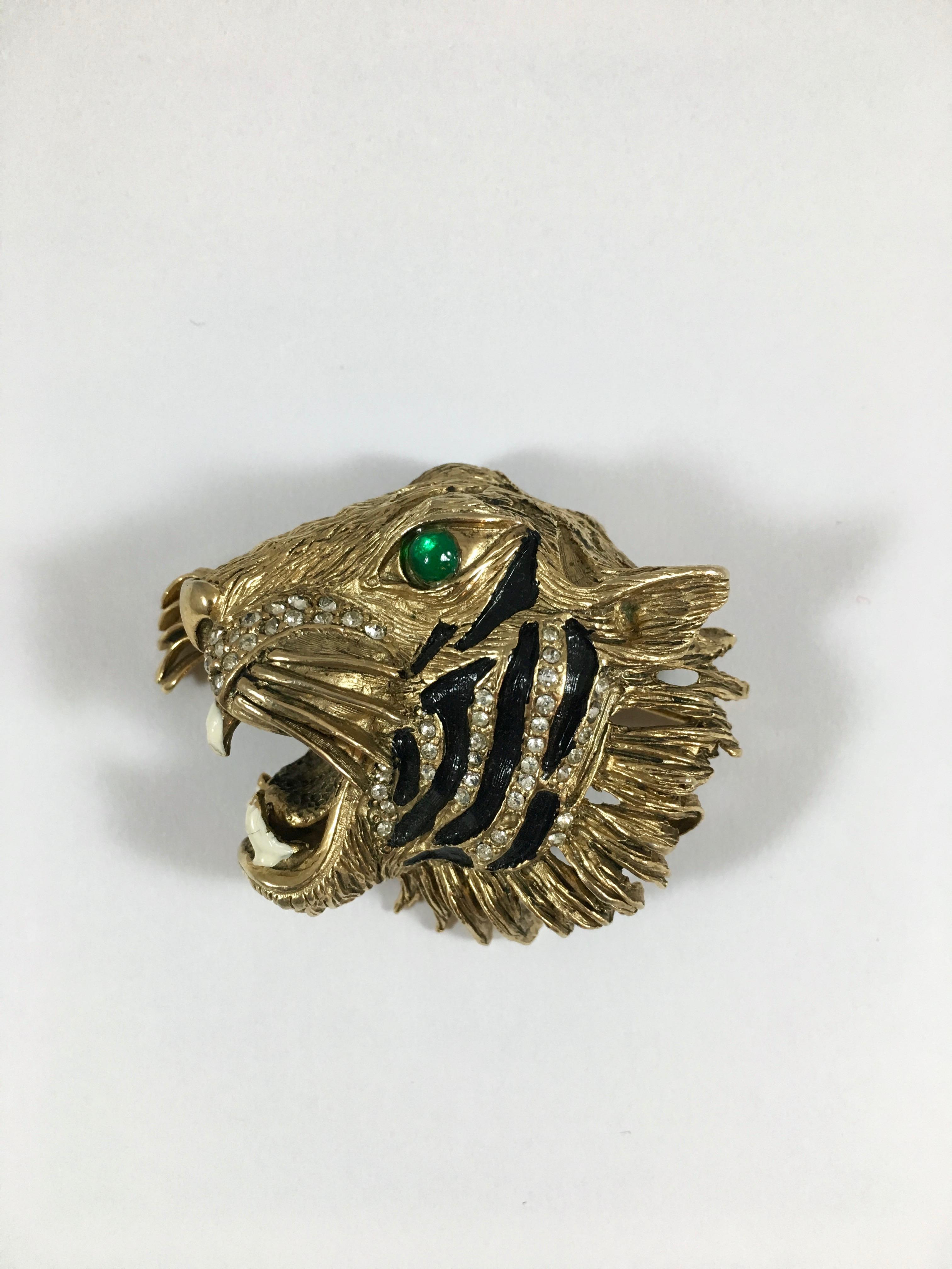 This is a fabulous 1940s Hattie Carnegie tiger head brooch. The design has been copied by Gucci and the brooch is now available in their Fall 2018 line (see image #8).  It is made out of a gold-toned metal and has black enamel stripes, white enamel