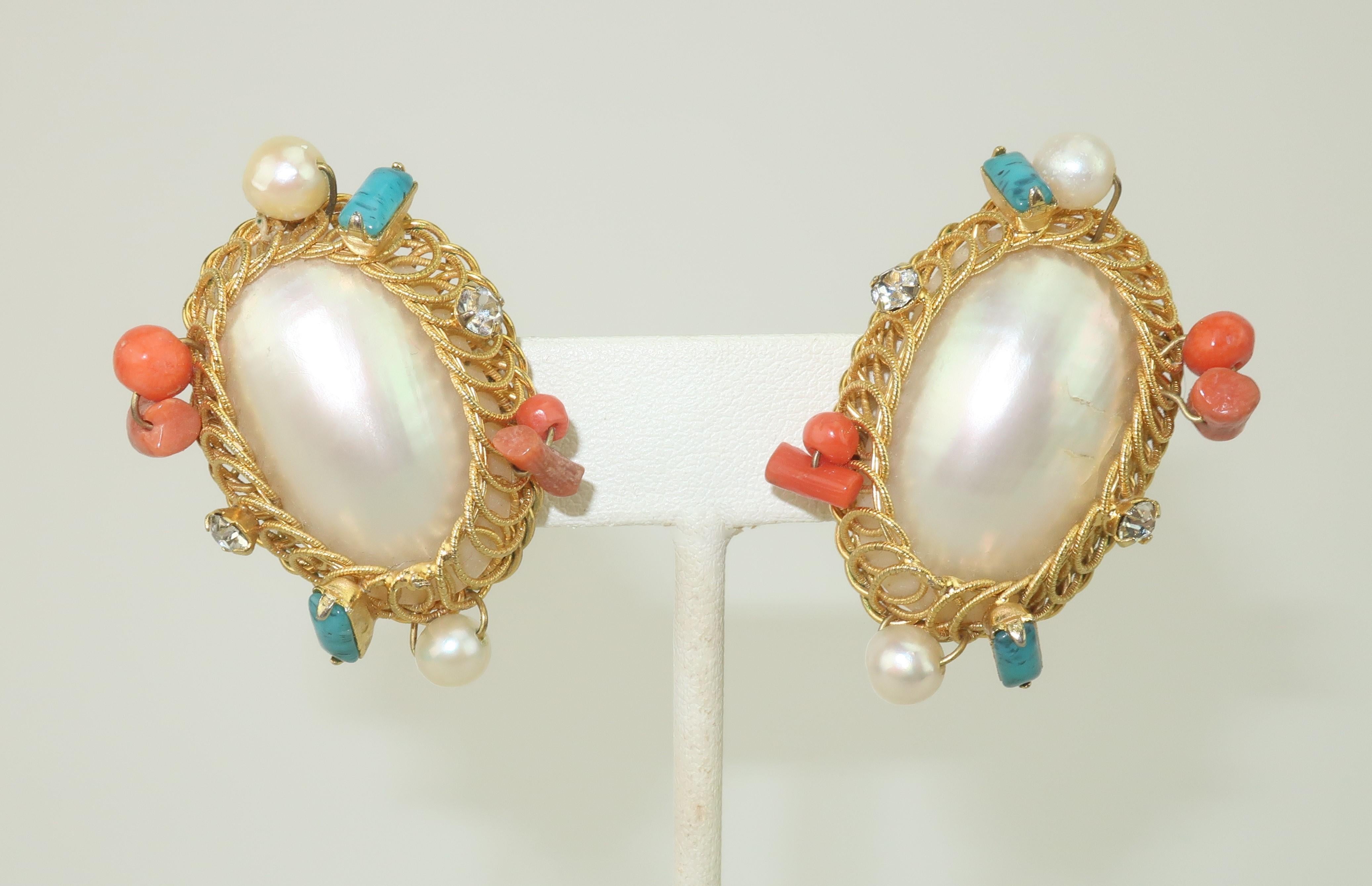 Vintage Hattie Carnegie set consisting of clip-on earrings and a pendant clip in mother-of-pearl framed by looped gold tone metal accented by faux glass coral and turquoise with rhinestones.  The clip-on earrings are designed to sit on an angle. 
