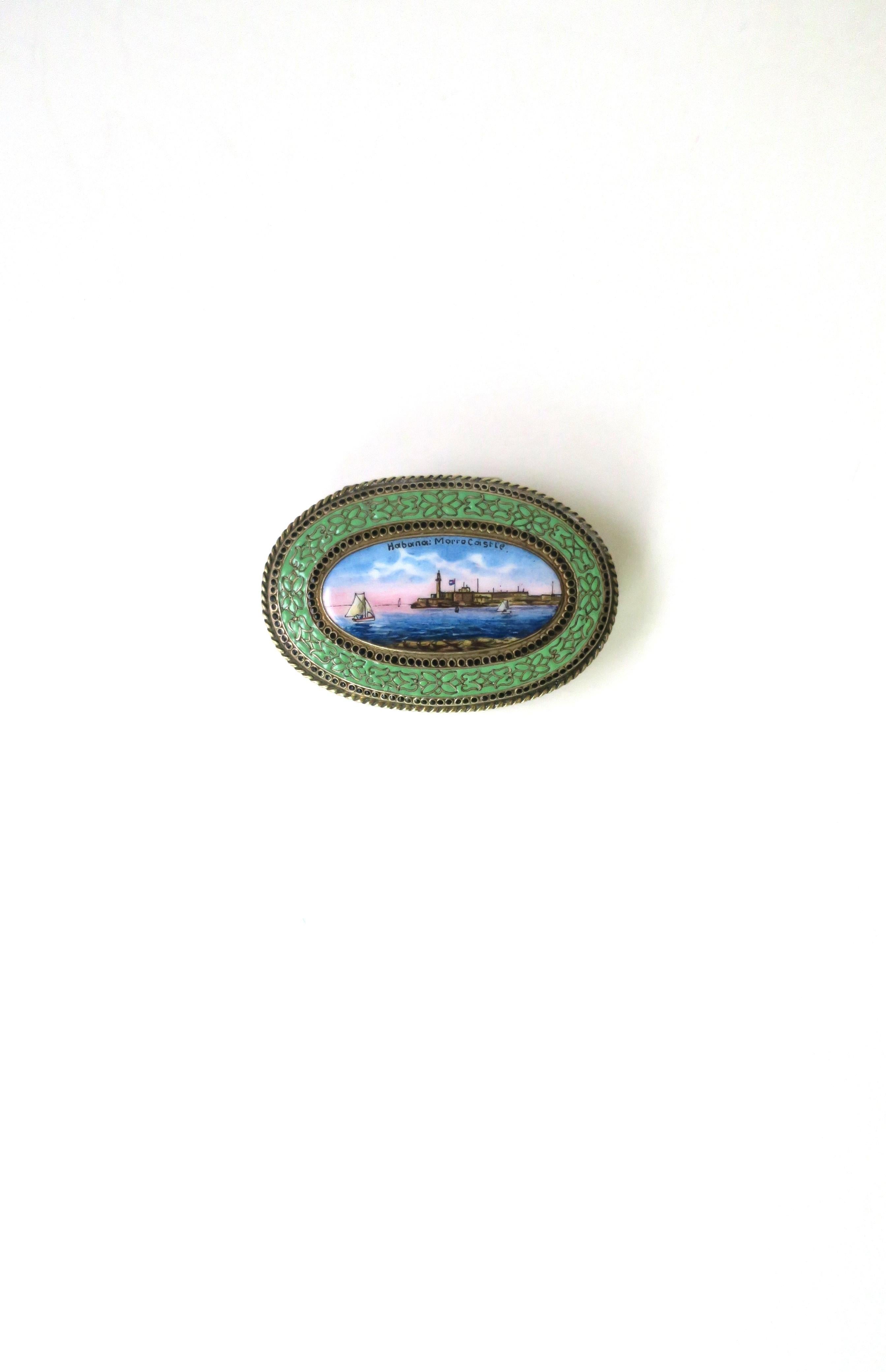 An oval metal and enamel trinket box with scene from Cuba. Box is made of alpacca metal (marked as shown in last image) with an enamel top depicting a sailboat, ocean water, and castle scene (Morro Castle), Havana, (Habana), Cuba. Across top reads
