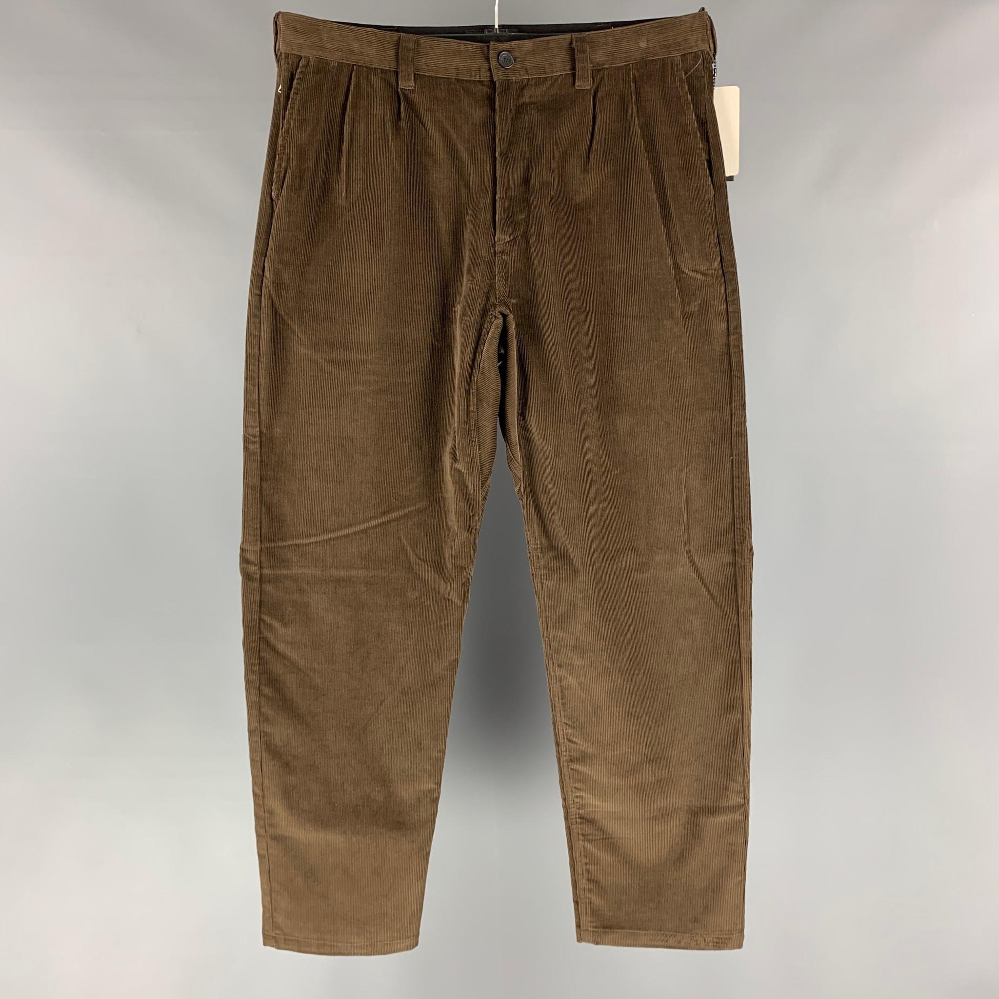 HAVEN 'Shop Pants' casual pants comes in a brown cotton corduroy fabric featuring an pleated style, a zip up pocket, snap button detail at waistband and a button fly closure. Made in Canada.

New With Tags.
Marked: L

Measurements:

Waist: 37