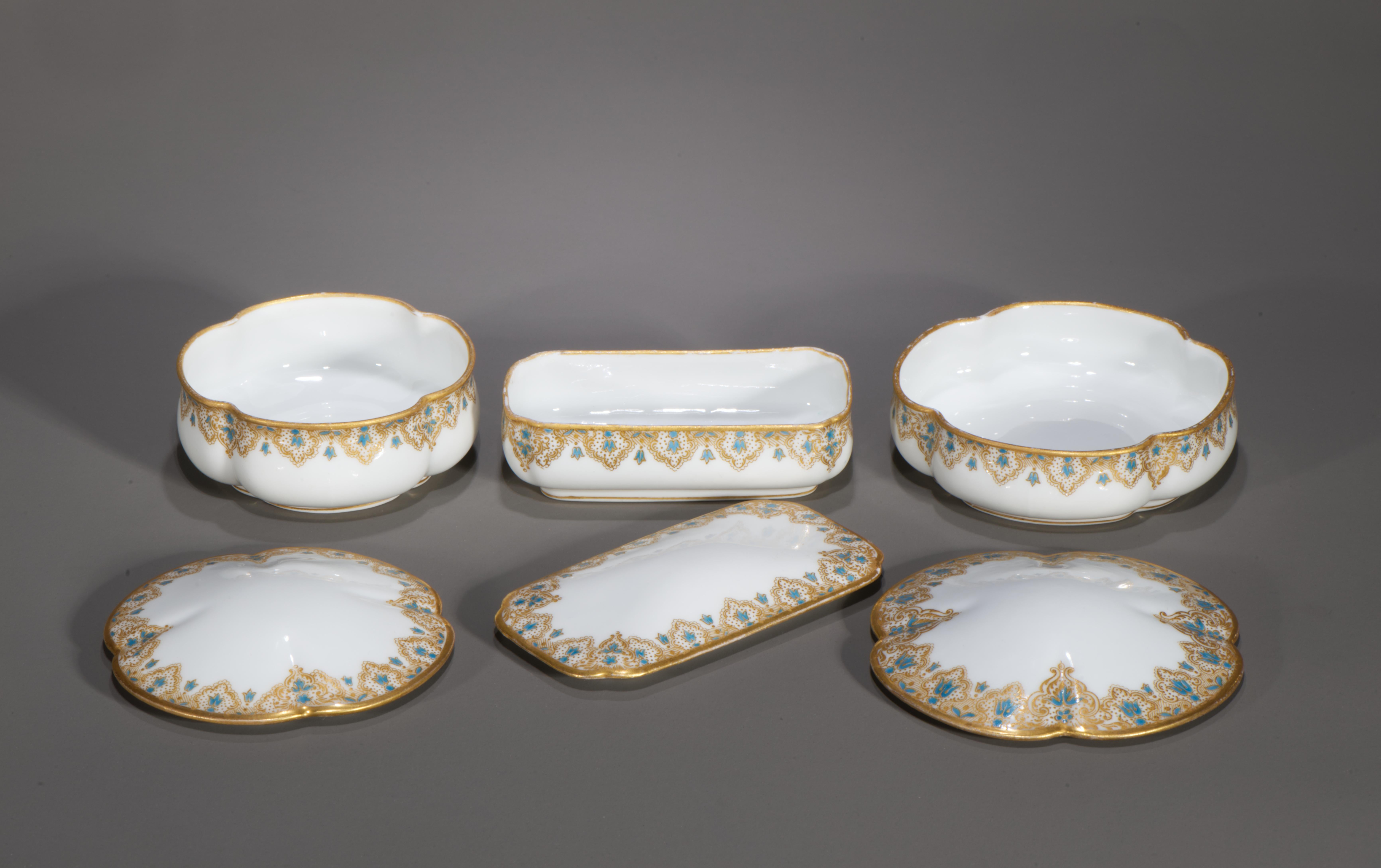 Antique set of 3 porcelain dresser boxes with lids features sculptural forms in different sizes and striking blue and gold decor. One box has rectangular shape, and two other boxes have squared forms with rounded scalloped corners, mirrored in the