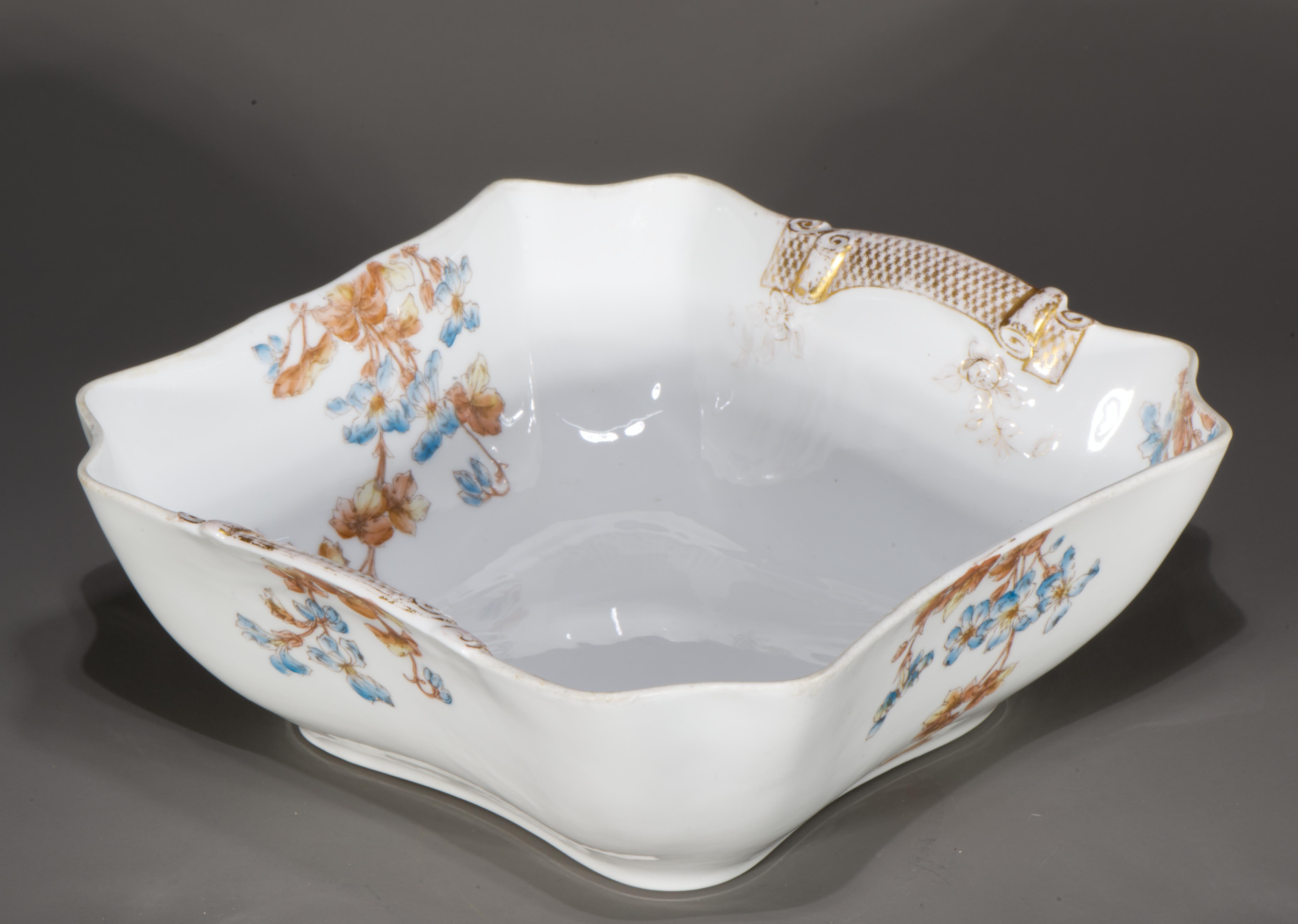 Antique porcelain serving or salad bowl features sculptural squared form with rounded scalloped corners. The bowl is hand decorated with an early variation of the classic Haviland 
