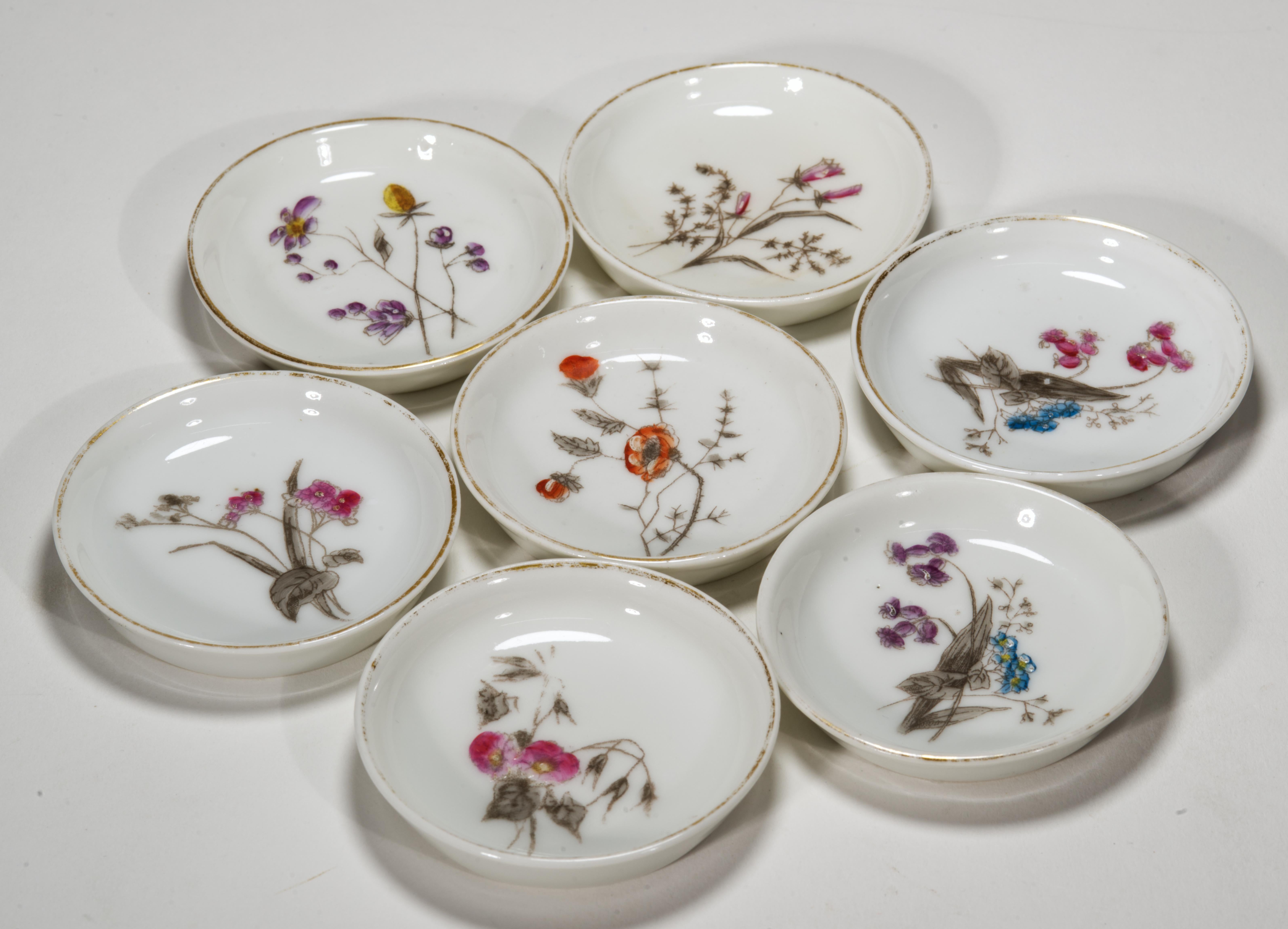 Antique round butter pats feature 6 different floral decors; one decor is repeated, but in the different colorway. The outlines of the decors were transferred on the porcelain blanks by decals and hand-painted over the lines by hand. Raised enamel