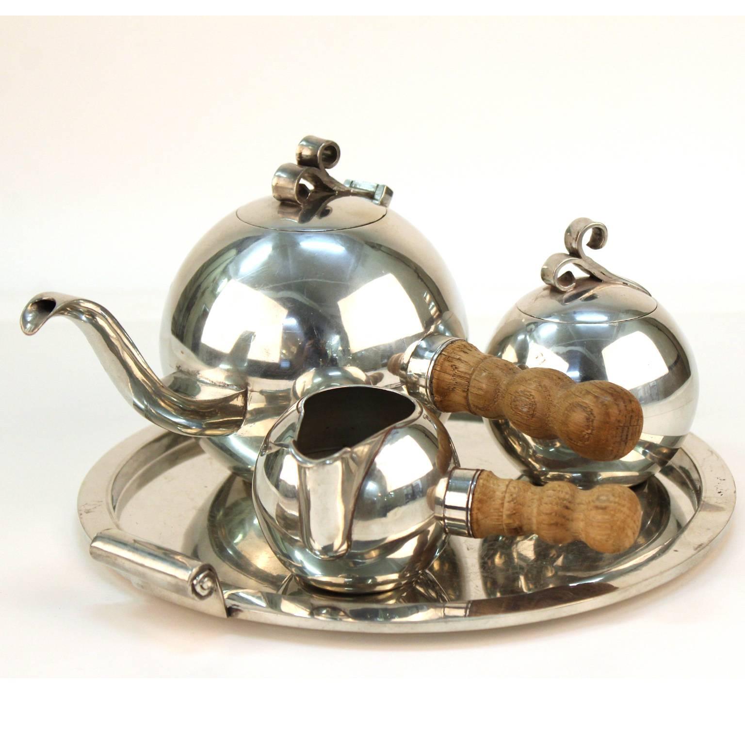 A Norwegian Art Deco pewter tea set made by Havstad in the 1920s-1930s. The set includes spherical tea pot, sugar bowl and creamer on a circular serving plate. Both the creamer and tea pot have an elegant sculpted wooden handle. Very good condition
