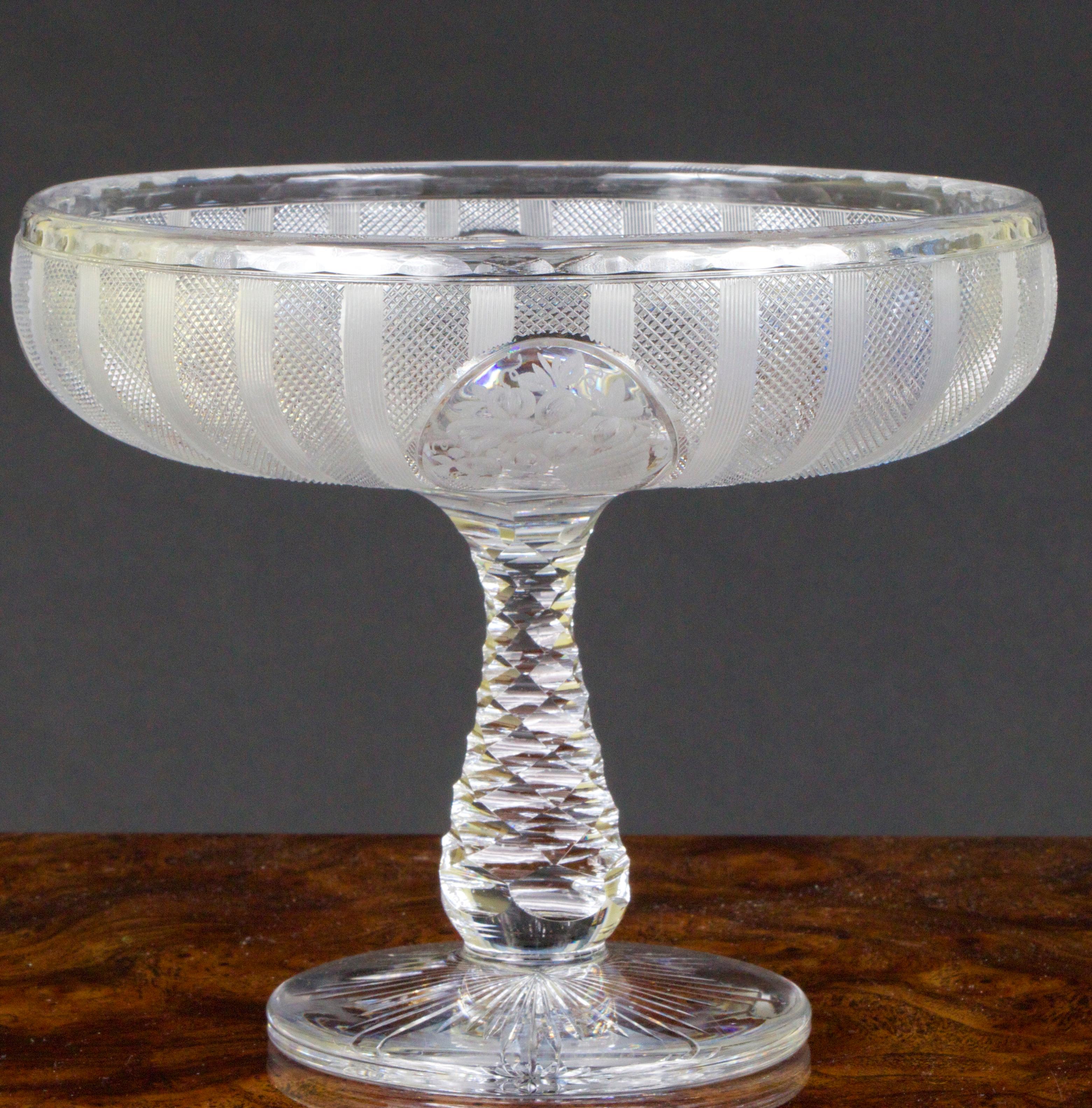Engraved Hawkes compote features four reserves: 2 of flower baskets and 2 of cornucopiae interspersed between divides of groups of vertical lines. The stem is 