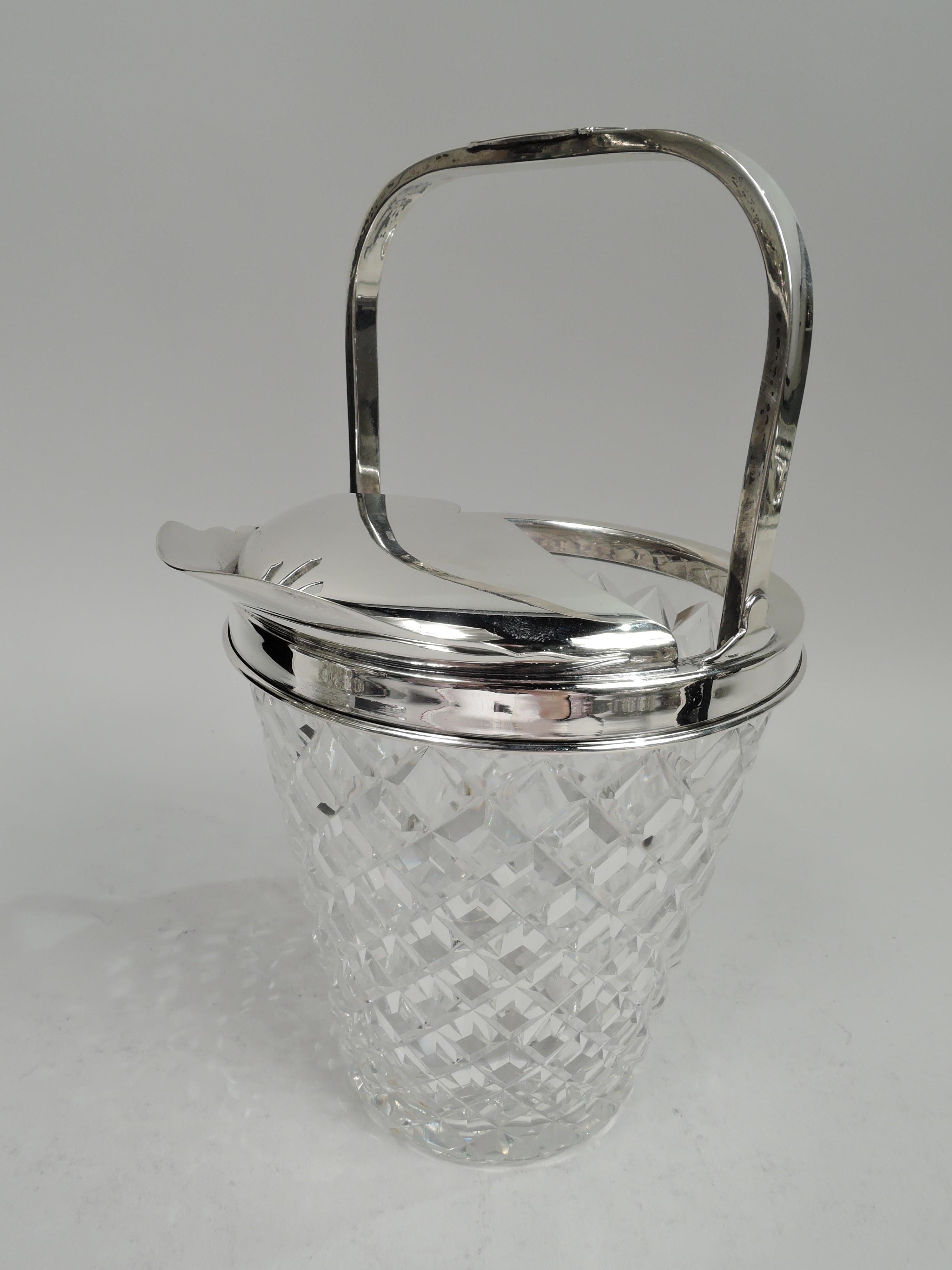 Mid-Century Modern sterling silver and glass ice bucket. Straight and tapering glass bowl with allover raised and faceted diaper pattern. Sterling silver collar with scrolled and pierced guard and scrolled u-form spout. Fixed scroll-mounted bracket
