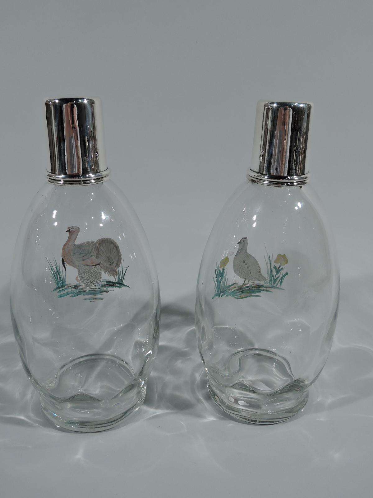 Pair of sterling silver and enameled glass decanters. Made by Hawkes in Corning, ca 1920. Each: Ovoid bottle with interior faceting, straight neck in sterling silver collar, and cylindrical cover (also sterling silver). Pontil mark. Clear glass with