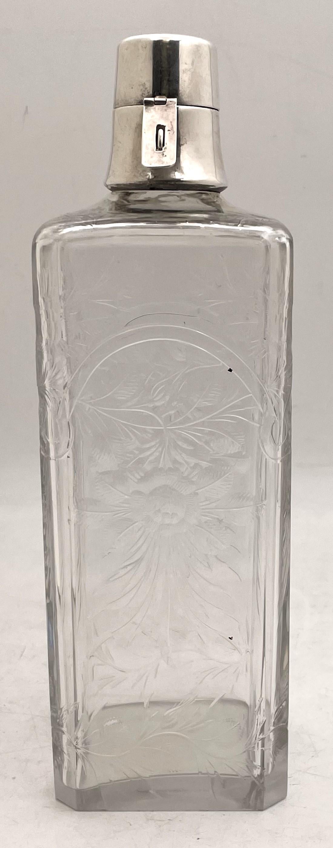 Hawkes decanter with a sterling silver cap and made of beautifully etched glass showcasing floral and natural motifs. From the early 20th century, it is in a geometrically inclined Art Deco style, measures 10 3/4'' in height by 3 1/2'' in depth, and